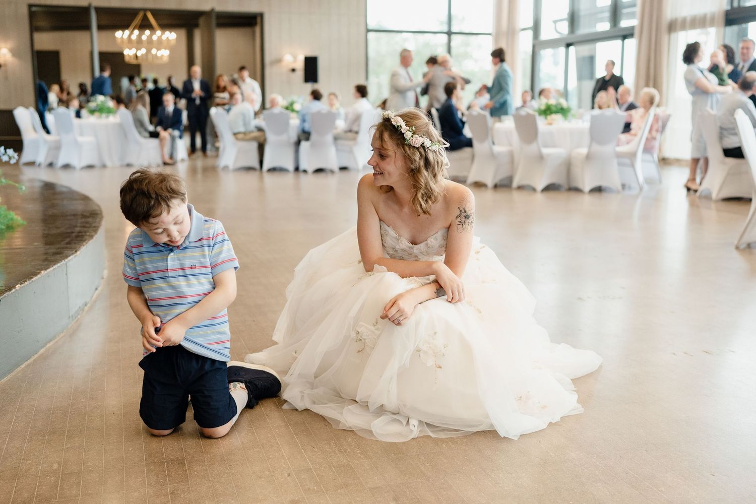 A sequence of five wedding photos showing a young child interacting with a bride in a white dress at a reception venue.
