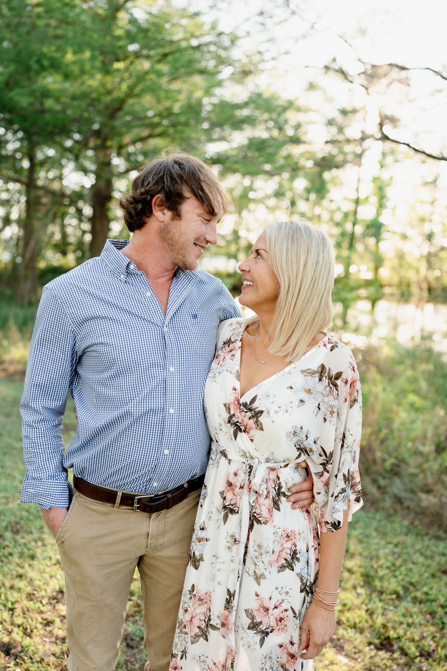 Couple sharing a romantic moment in a sunlit forest setting wearing coordinated casual outfits.