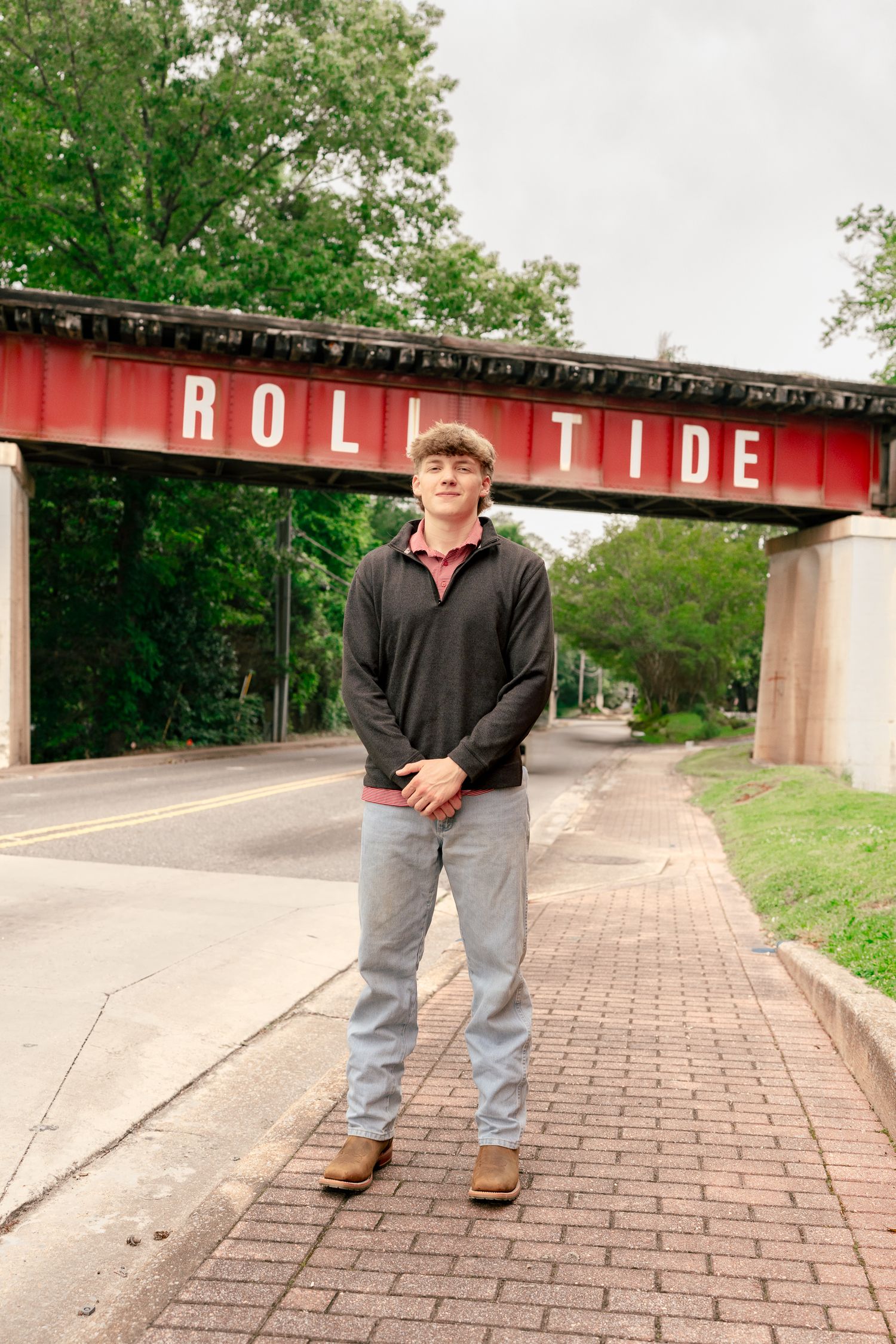A casual portrait of a student standing beneath the Roll Tide bridge at Alabama.