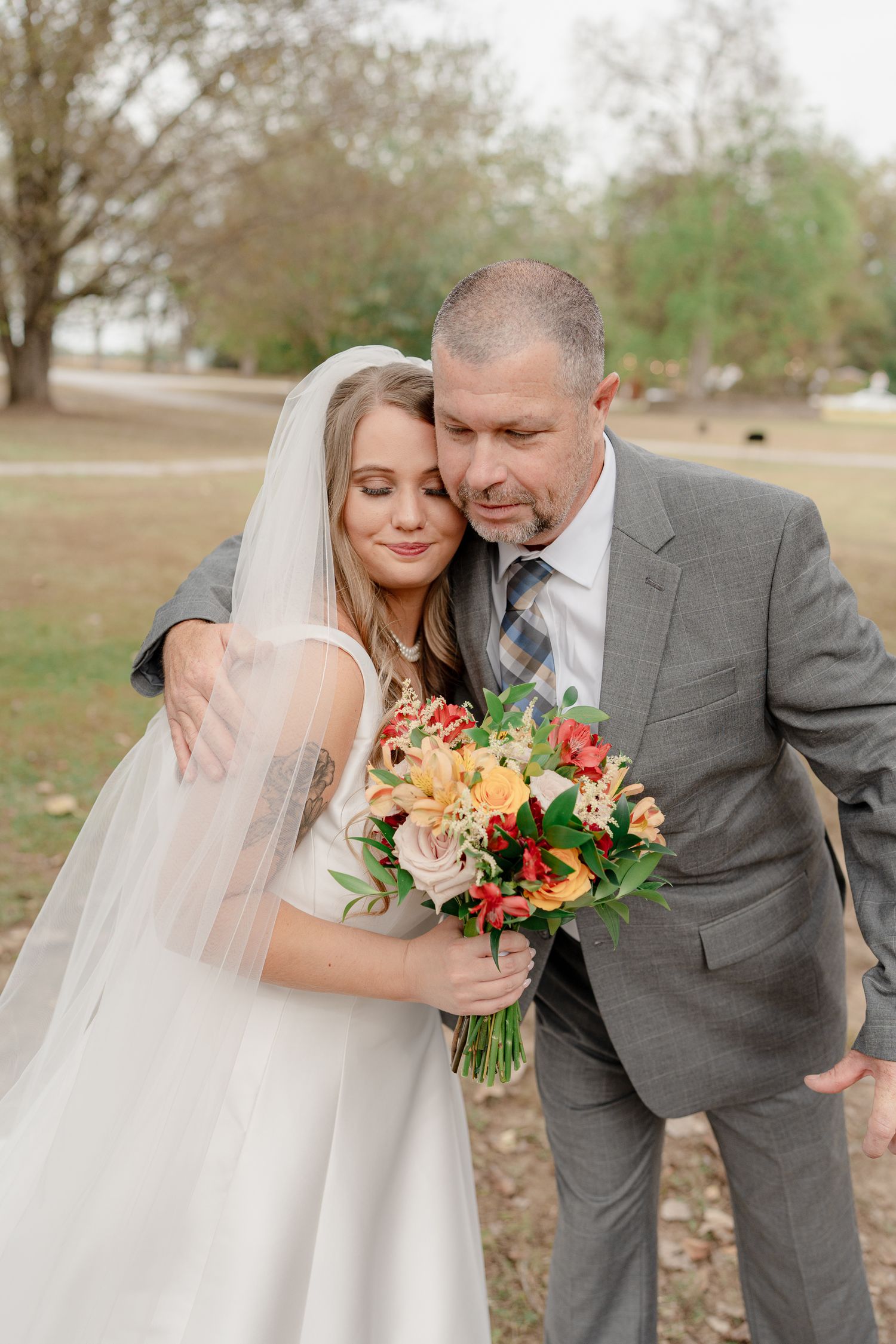 Romantic outdoor wedding portraits featuring a bridal bouquet with peach and red blooms against a natural backdrop.