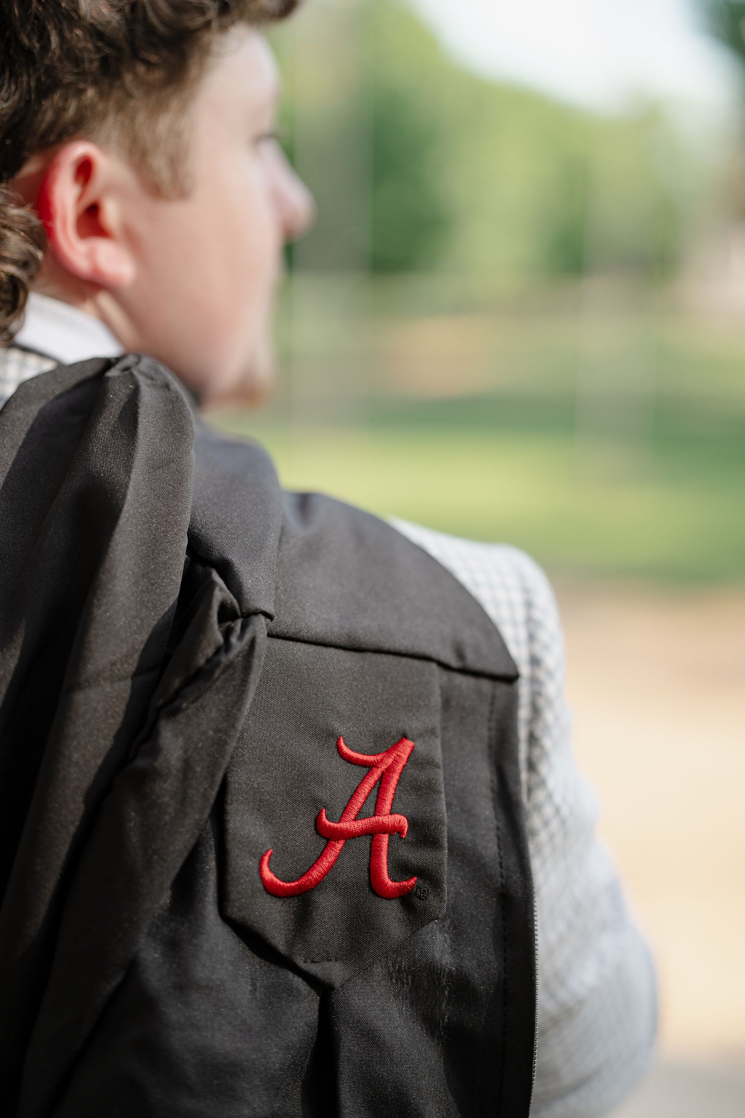 Close-up of University of Alabama crimson Script A embroidered on black graduation gown.