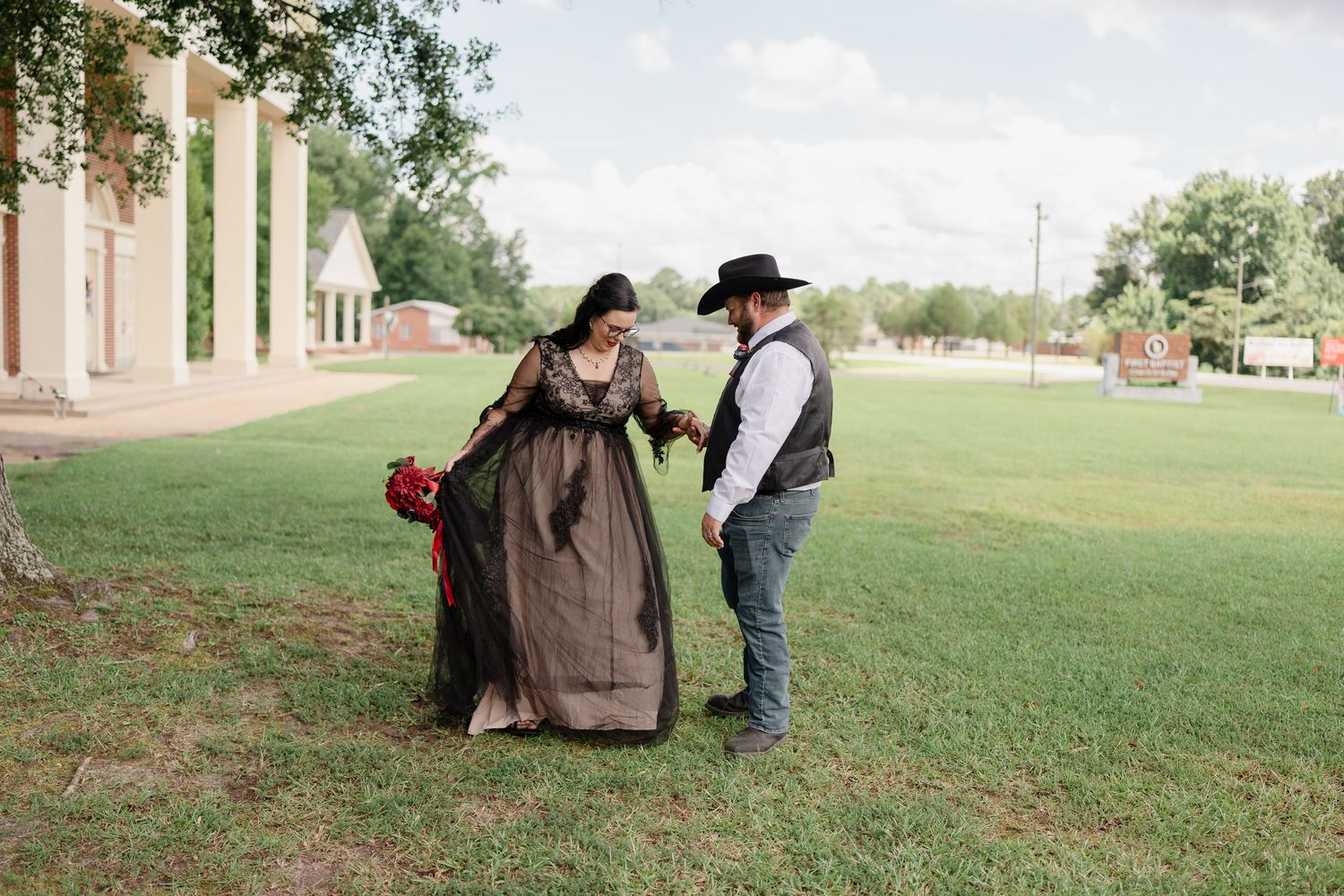 Wedding couple in western-themed attire shares romantic moment outdoors.