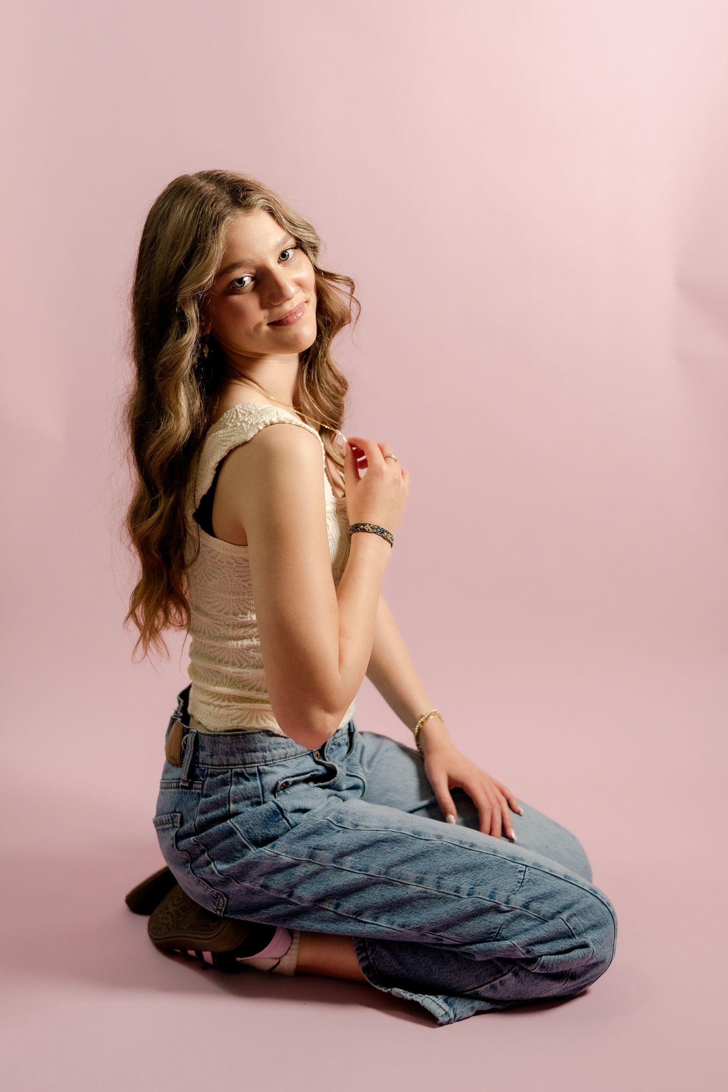 Artistic fashion portrait in casual wear against soft pink studio backdrop.