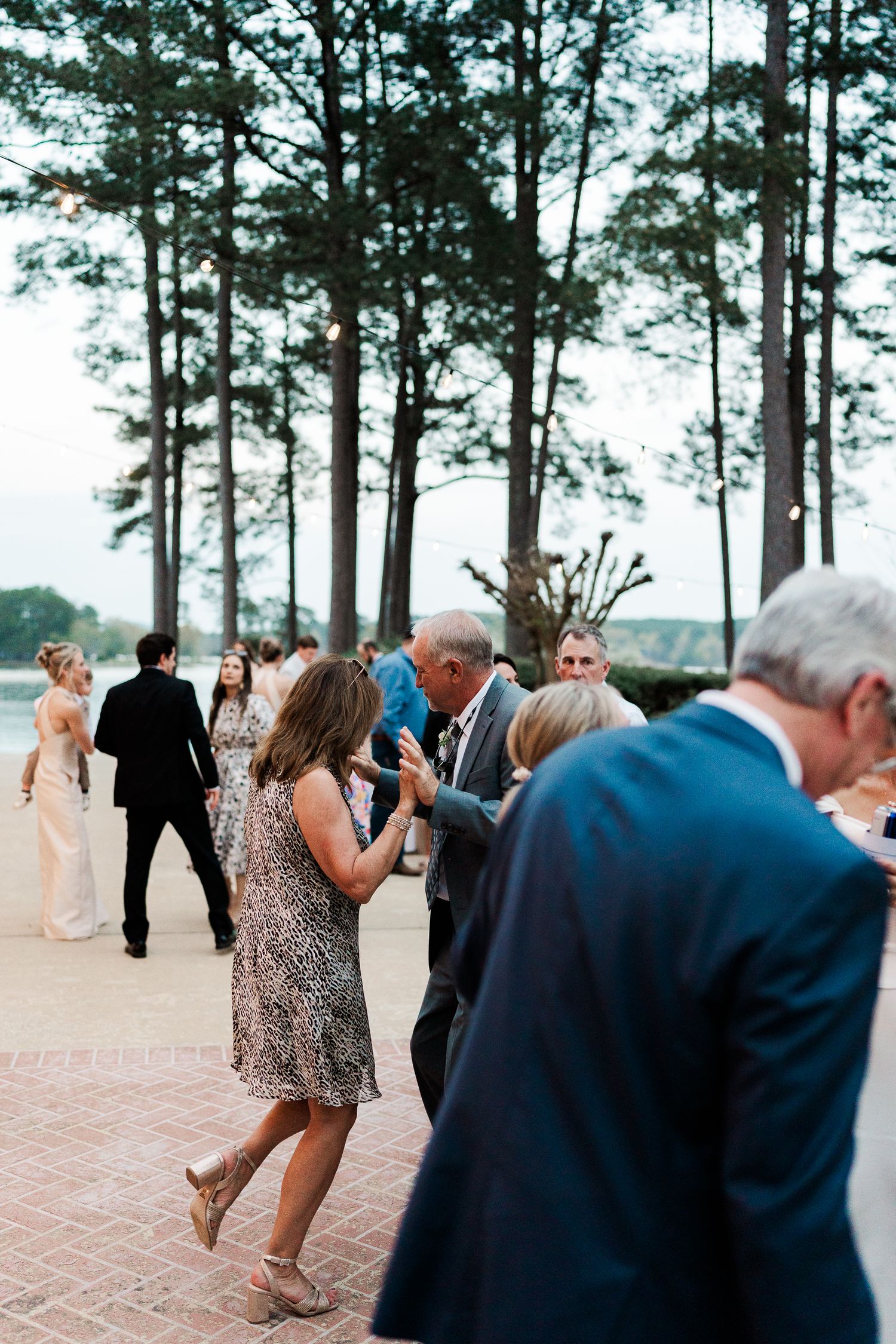Wedding celebration on a brick patio with tall pine trees creating a natural backdrop.