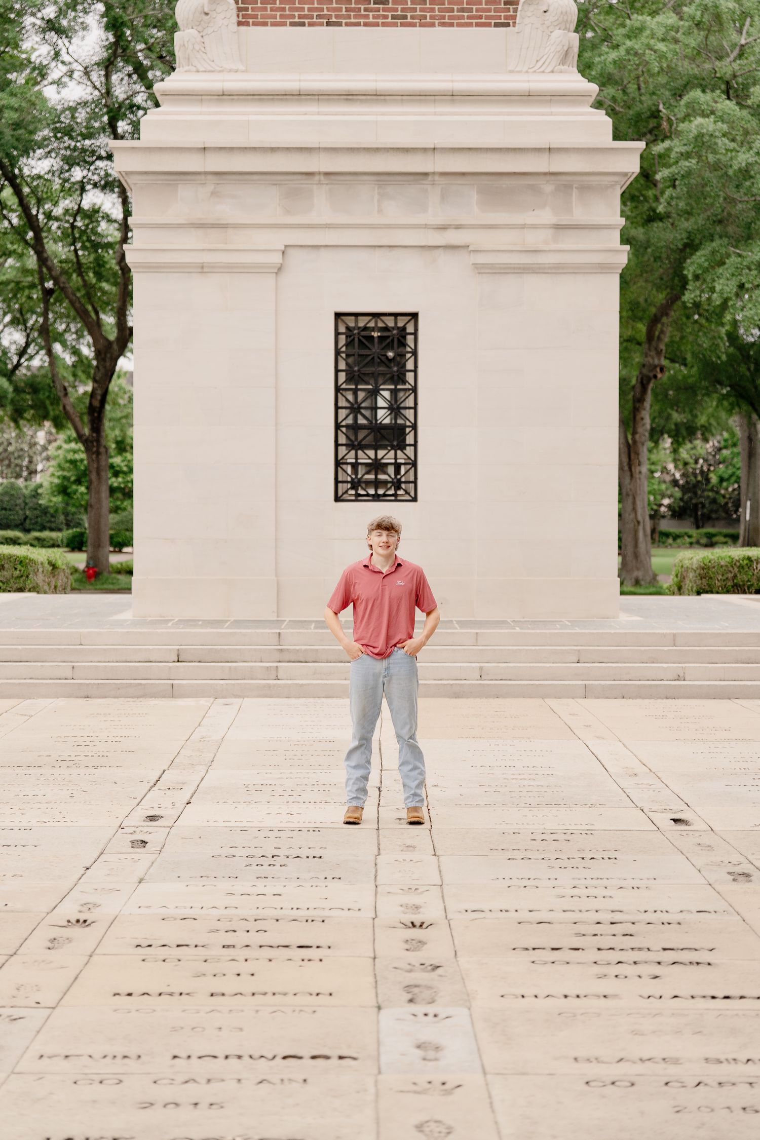 Person stands on engraved stone pavement in front of Denny Chimes memorial wall.