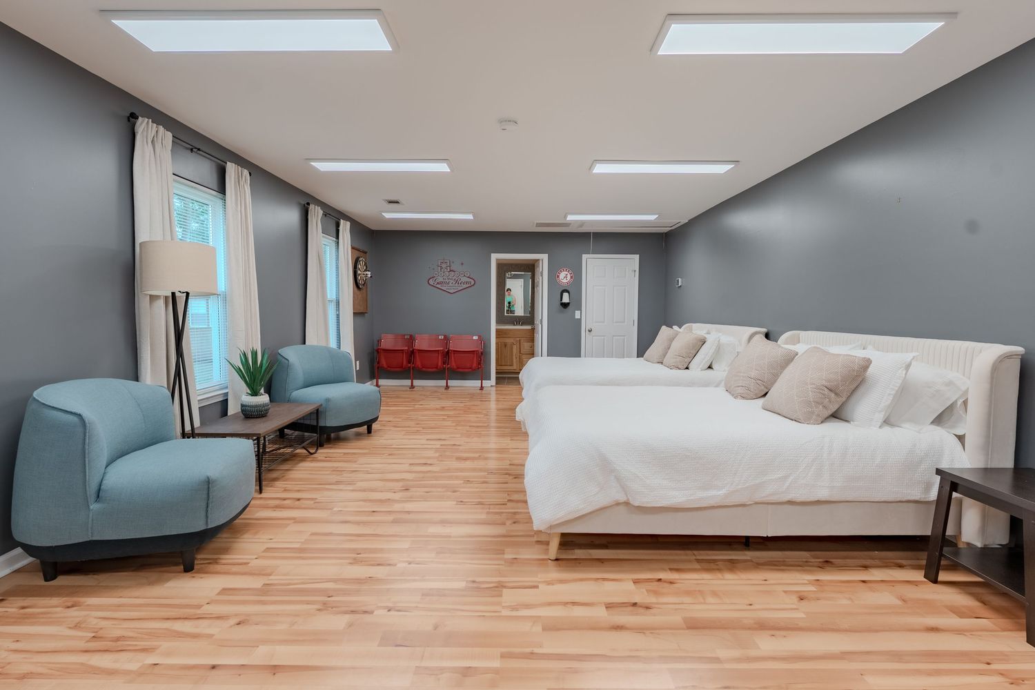 Modern bedroom interior with wooden flooring, skylights, and minimalist gray walls showcasing contemporary design elements.