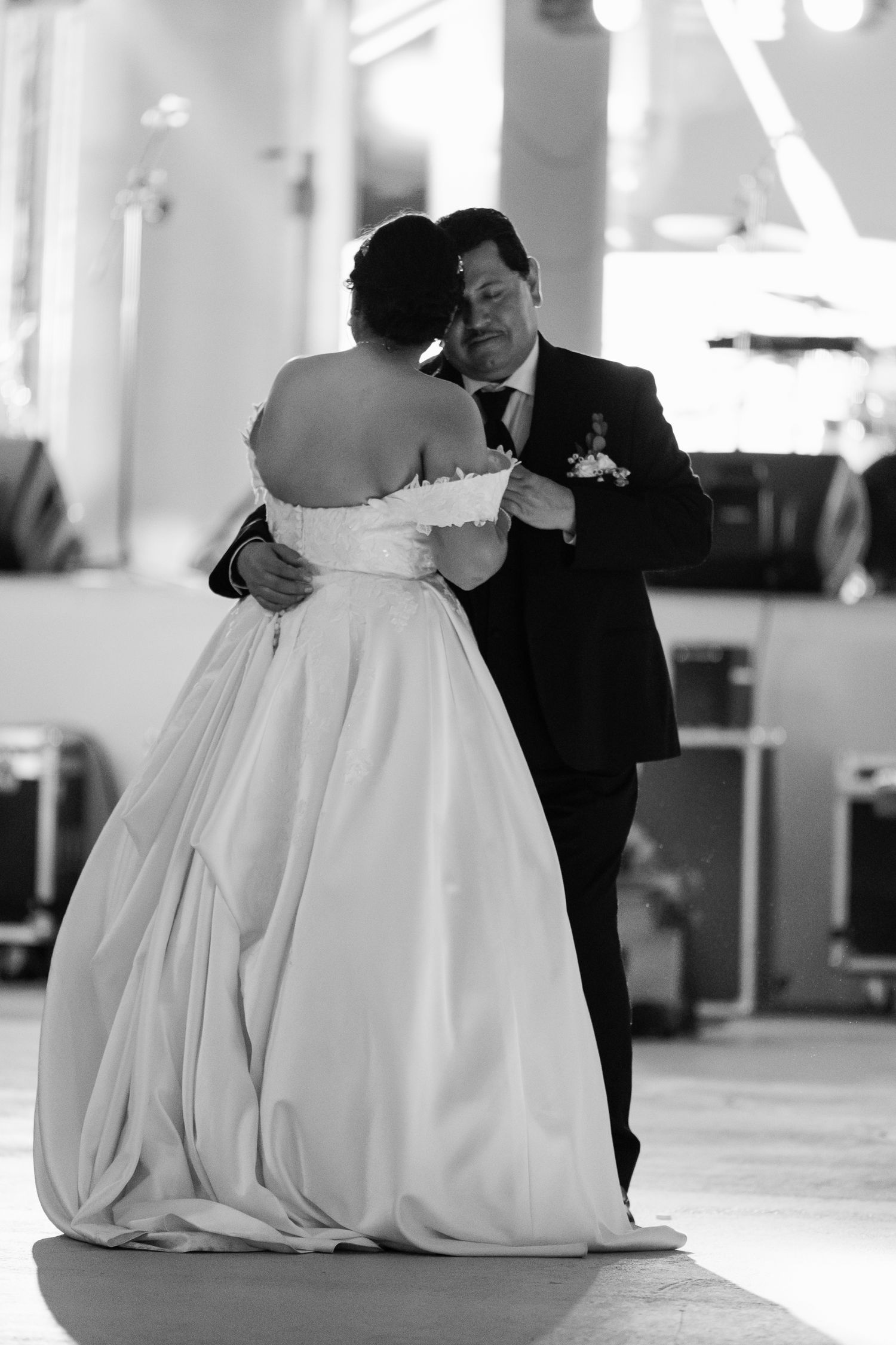 A black and white photo of a couple dancing at their wedding reception, with the bride in a strapless ballgown.