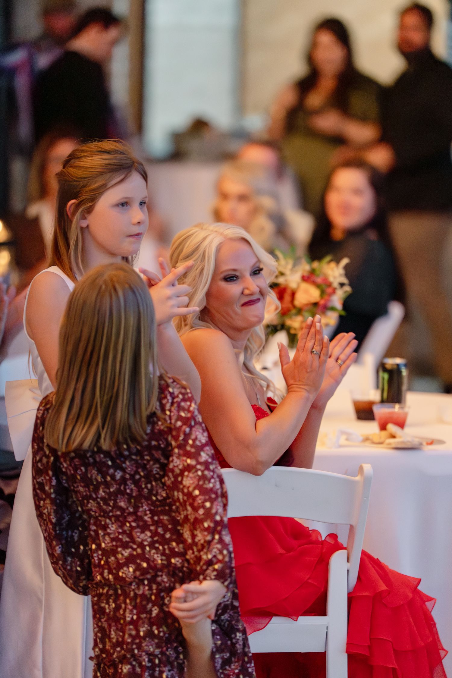 Wedding reception guests in burgundy dresses enjoying celebration at white-clothed tables.