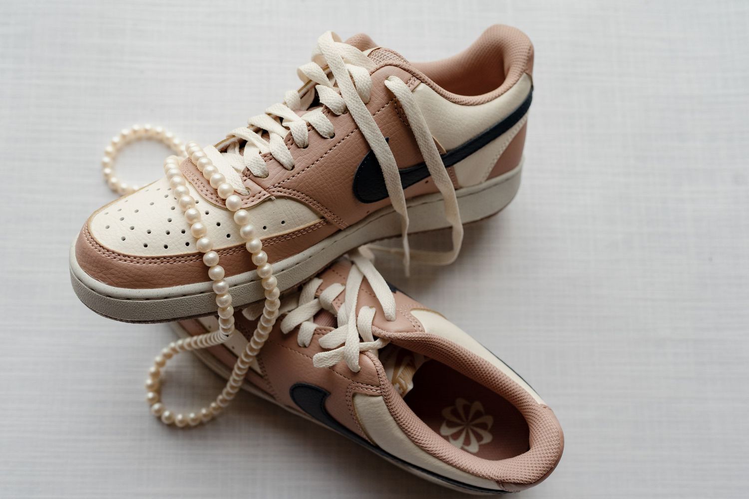 Pair of light pink and white sneakers shown from different angles on a neutral background.