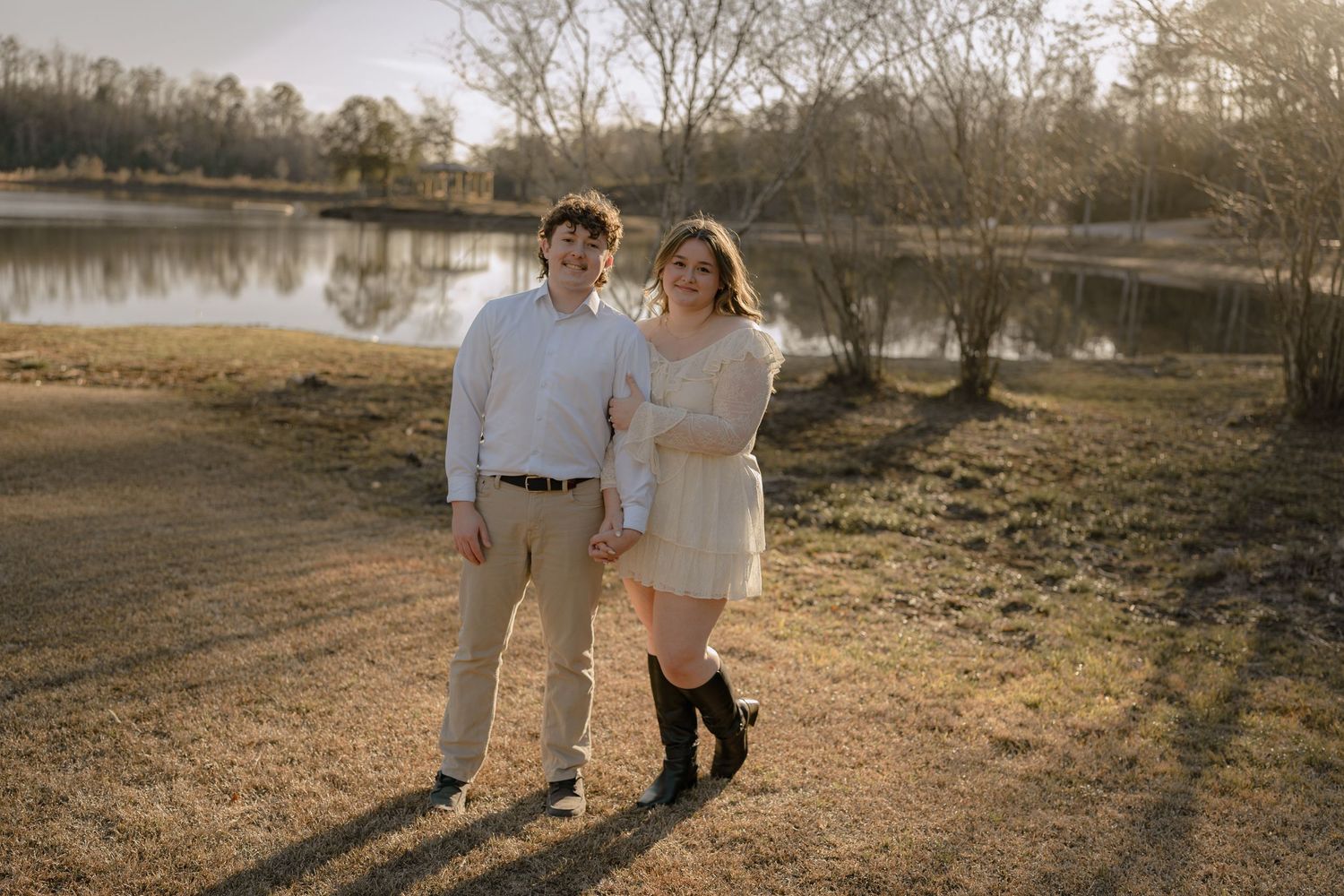 Smiling couple posing together near a peaceful lake during golden hour in nature.