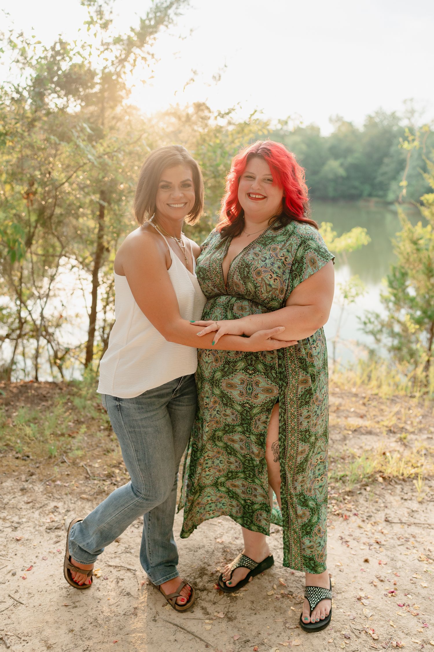 Friends share joyful embraces and laughter during a lakeside photo session.