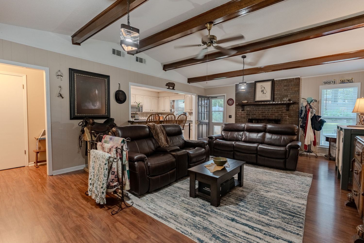 Cozy living room with exposed wooden beams, leather sectional sofa, and decorative area rug on hardwood floors.