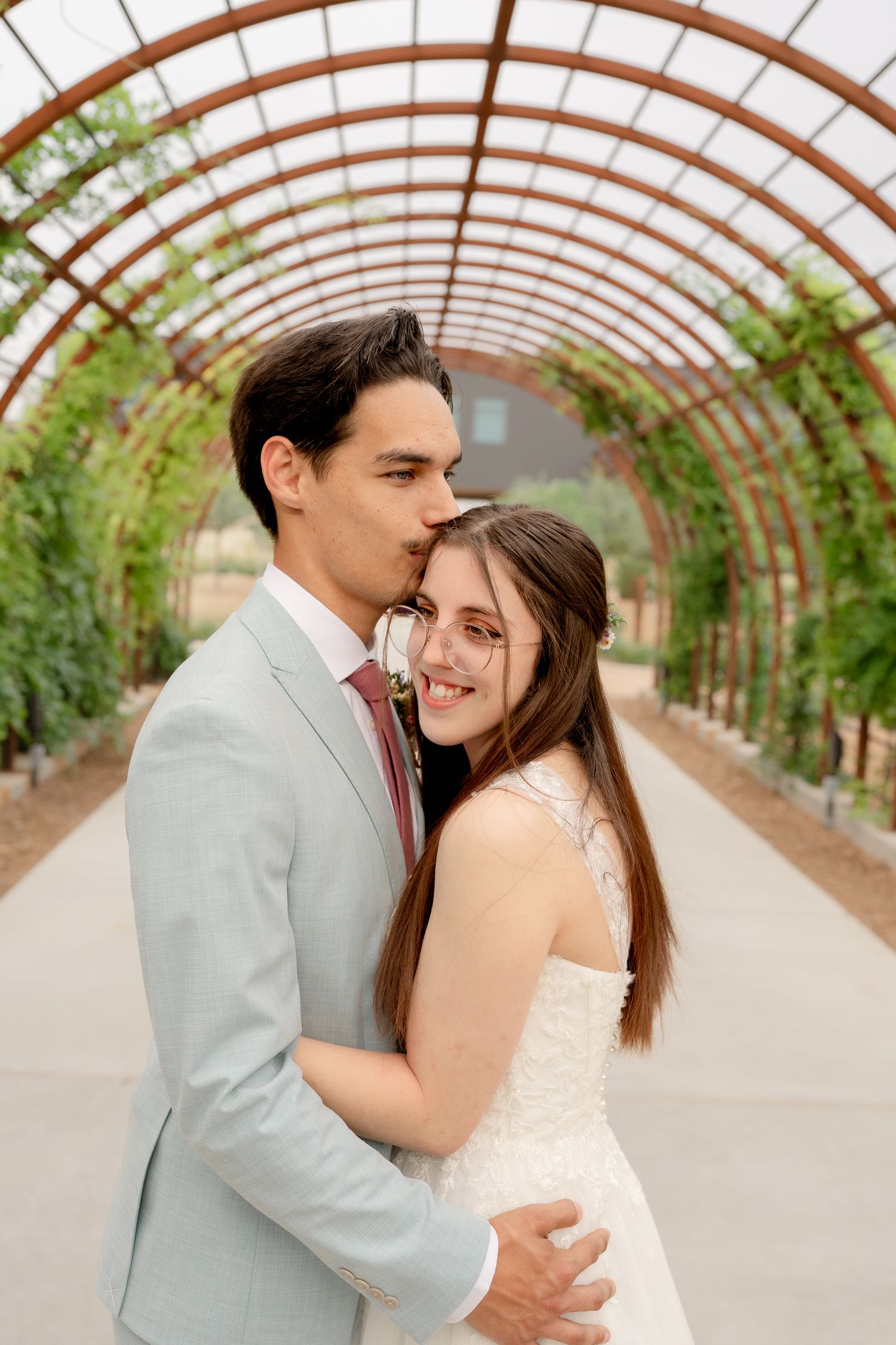 Intimate wedding photos captured in a greenhouse tunnel with natural lighting and greenery.