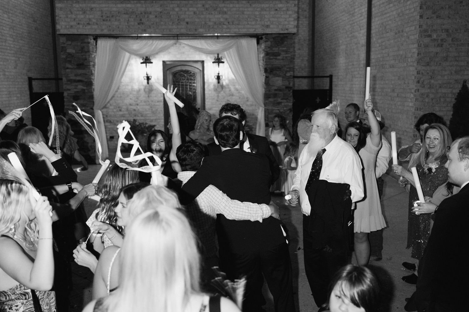 Wedding reception dance floor filled with celebrating guests under dim lighting.