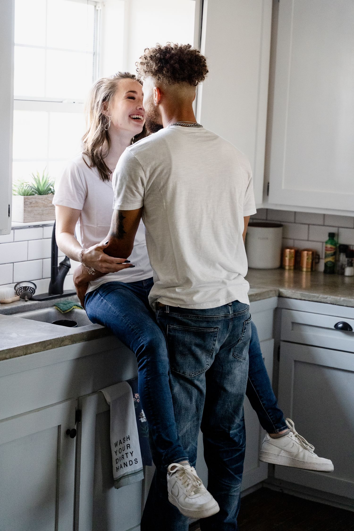 Romantic couple sharing intimate moment in modern white kitchen interior.