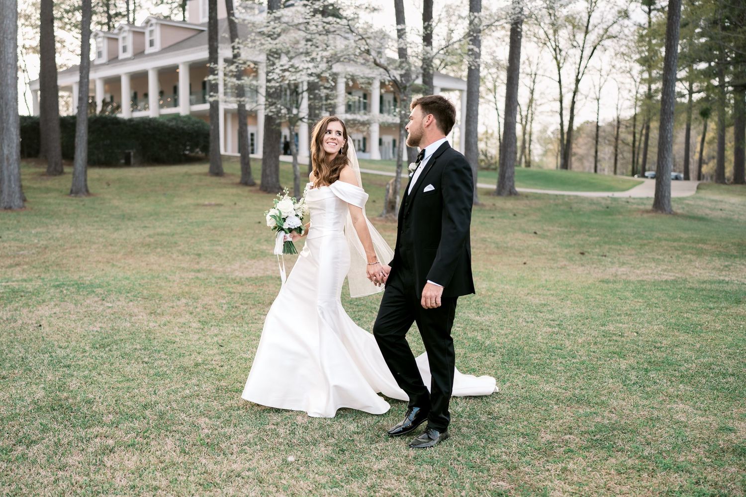 Elegant outdoor wedding portrait with couple posing on manicured lawn.