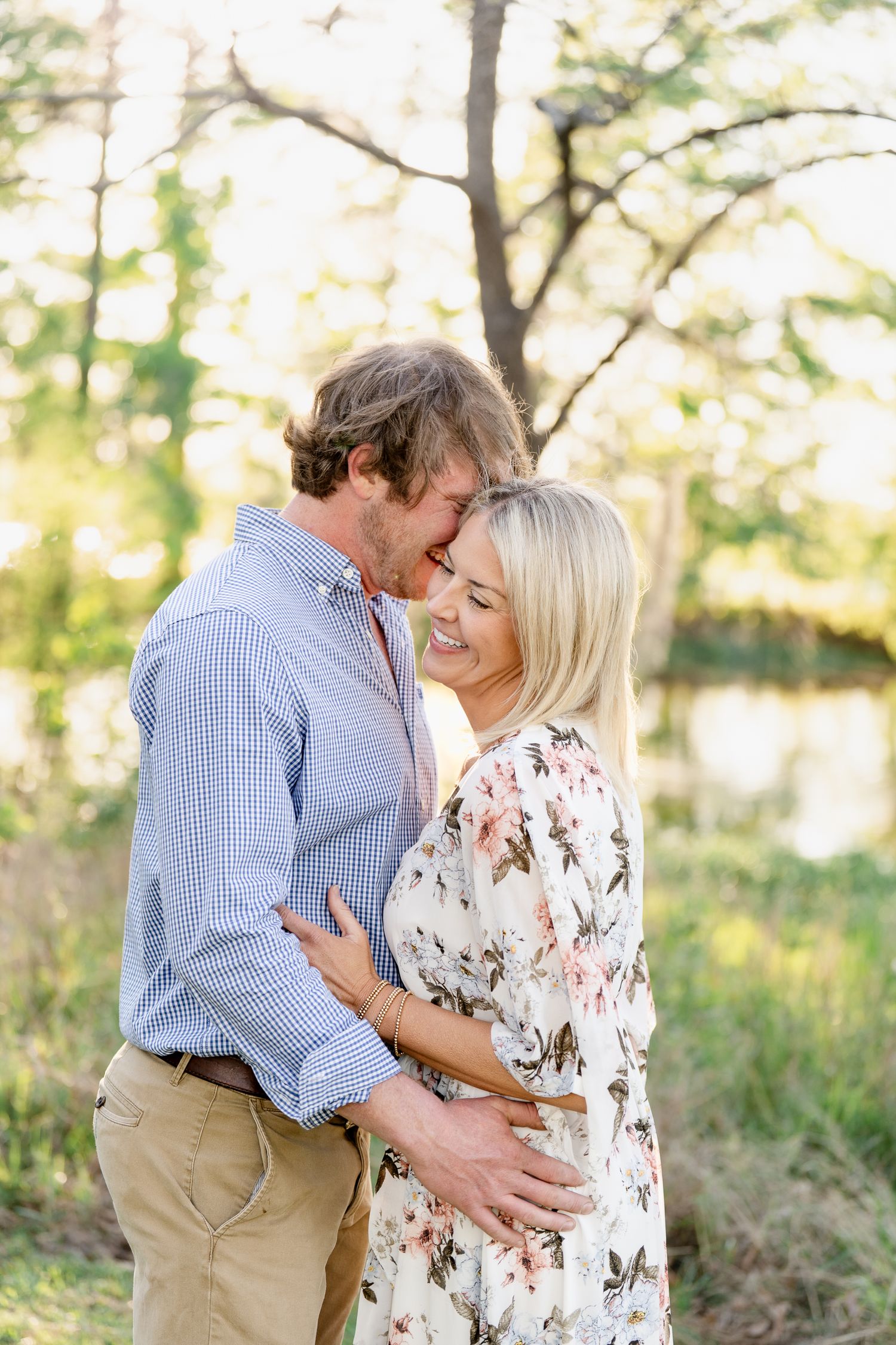 Intimate moment between couple in casual attire during golden hour forest photoshoot.