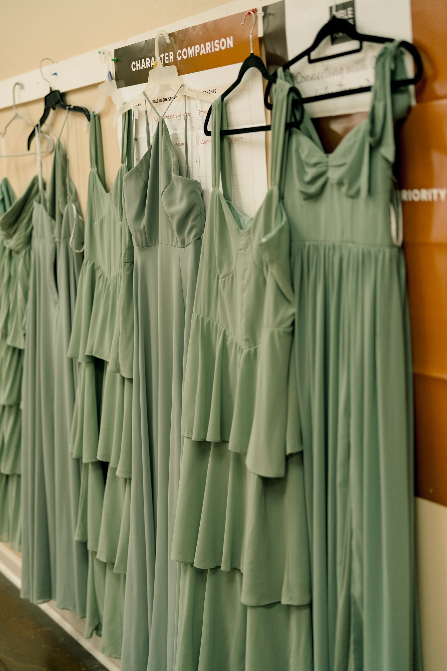 Sage green bridesmaid dresses hanging on a rack ready for a wedding.