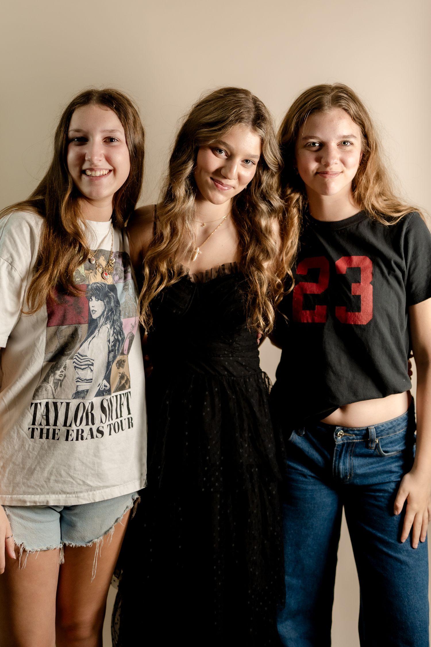 Friends pose together in casual attire during a fun photoshoot against a white backdrop.