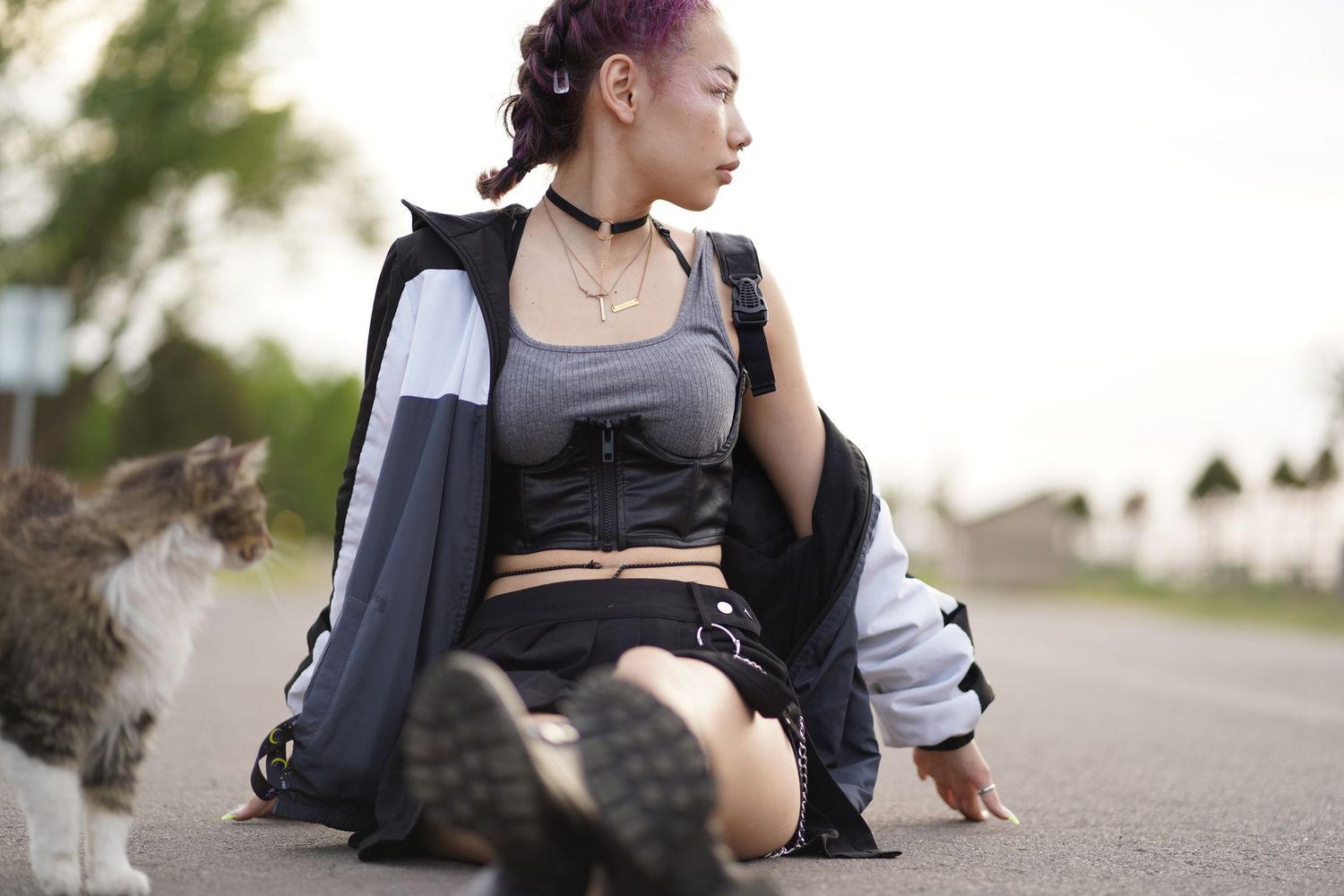 Casual street style pose featuring black and white sportswear on asphalt road.