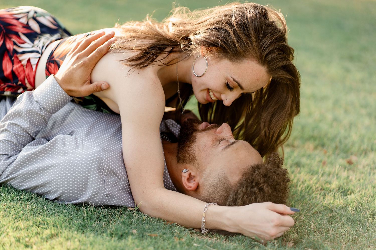A couple lies together on grass during an intimate outdoor photoshoot.