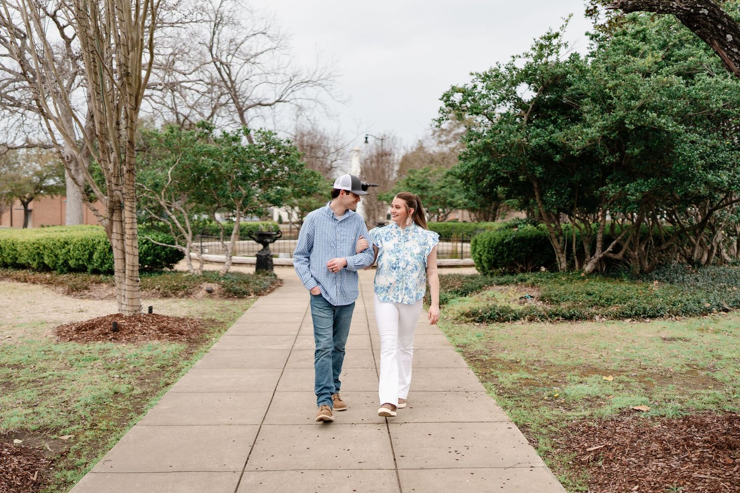 A couple walking together on a garden pathway during winter.