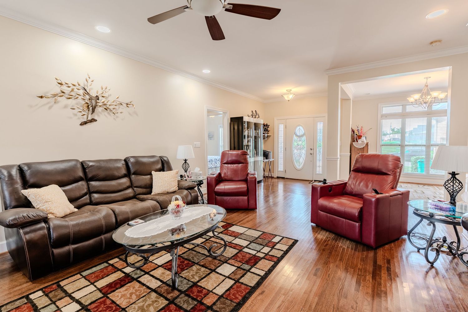 Modern living room with brown leather sectional sofa, red accent chair, and geometric patterned area rug.