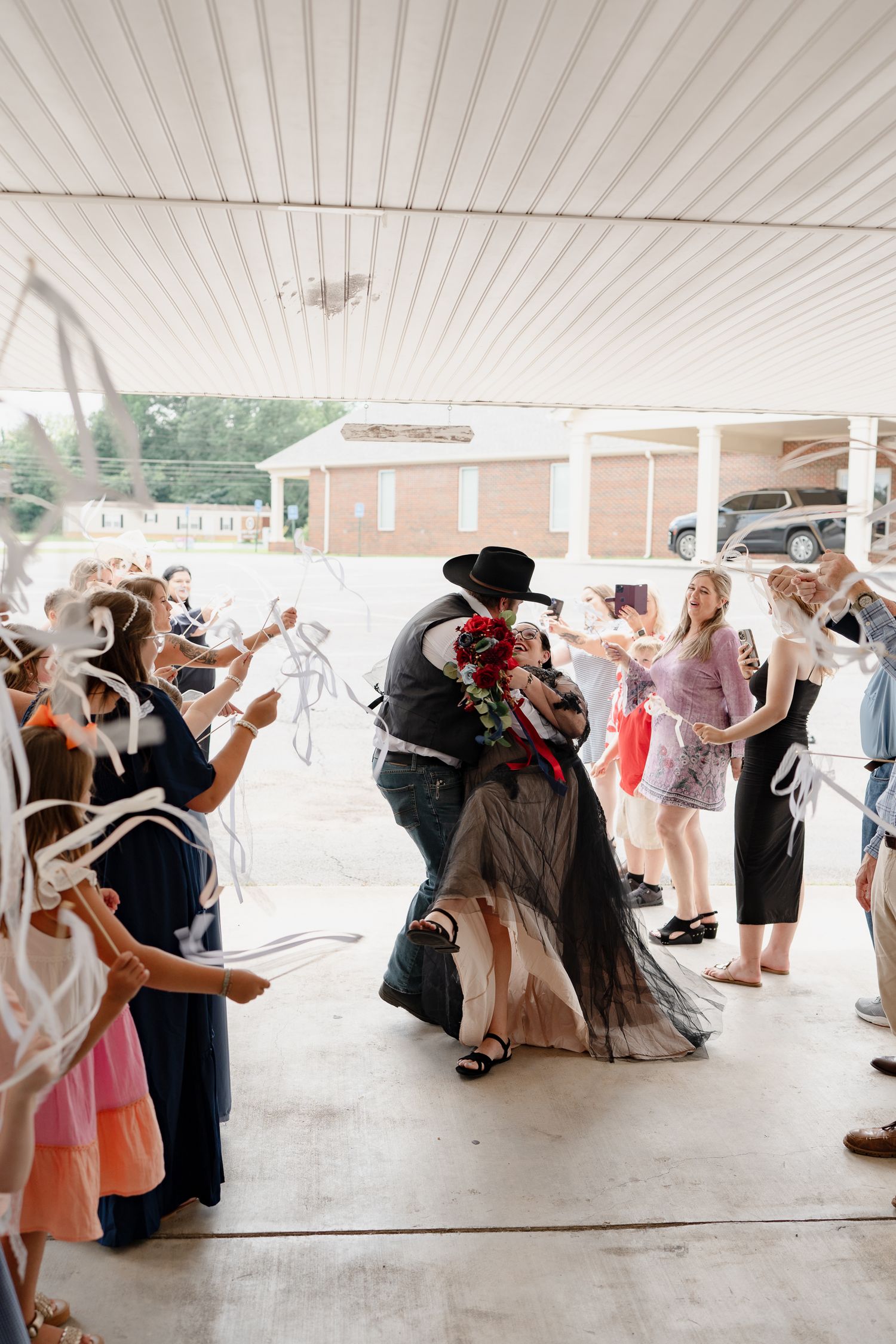 Couples dancing at an outdoor wedding reception under a white covered pavilion.