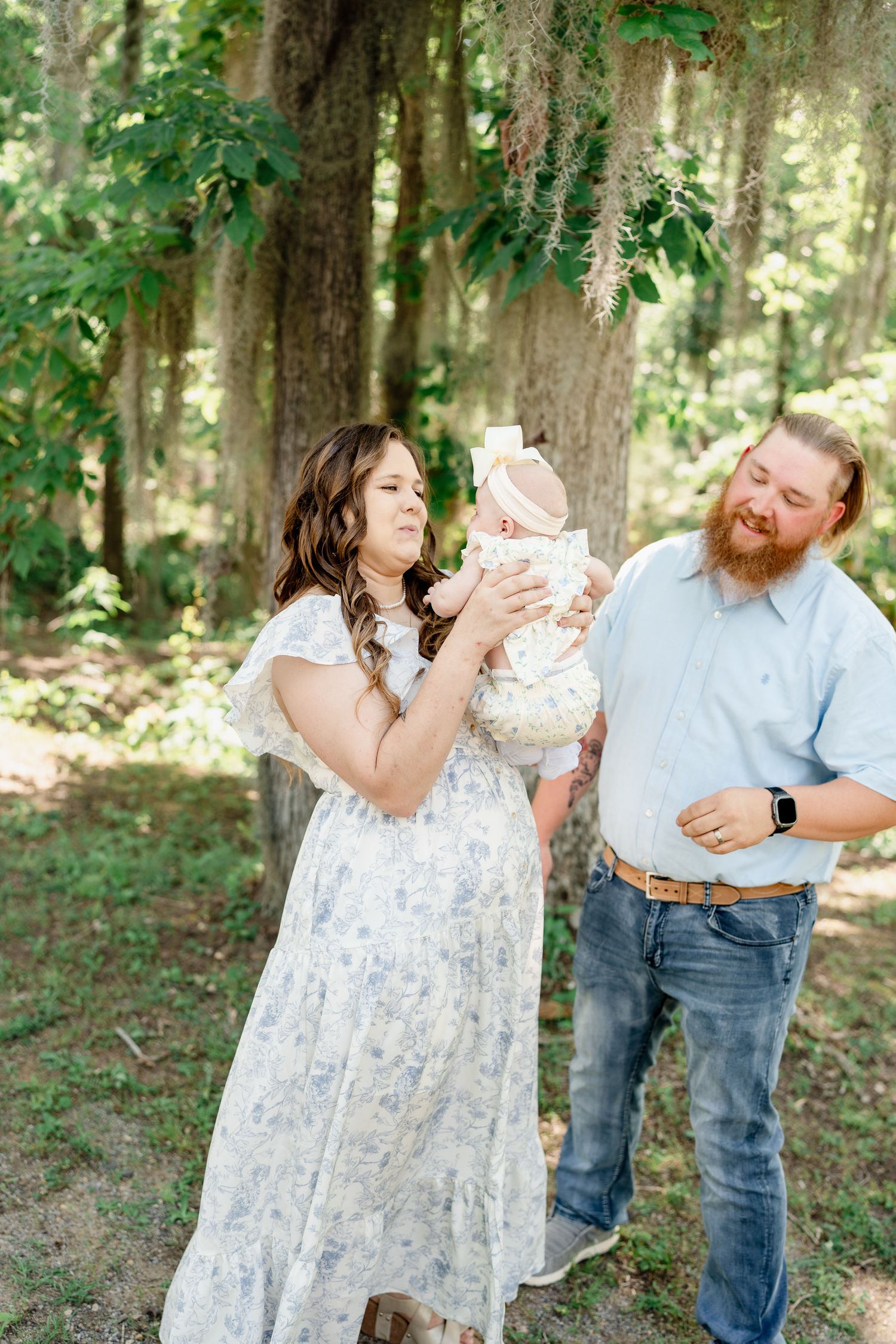 Family enjoying playful moments together during forest photoshoot in natural lighting.