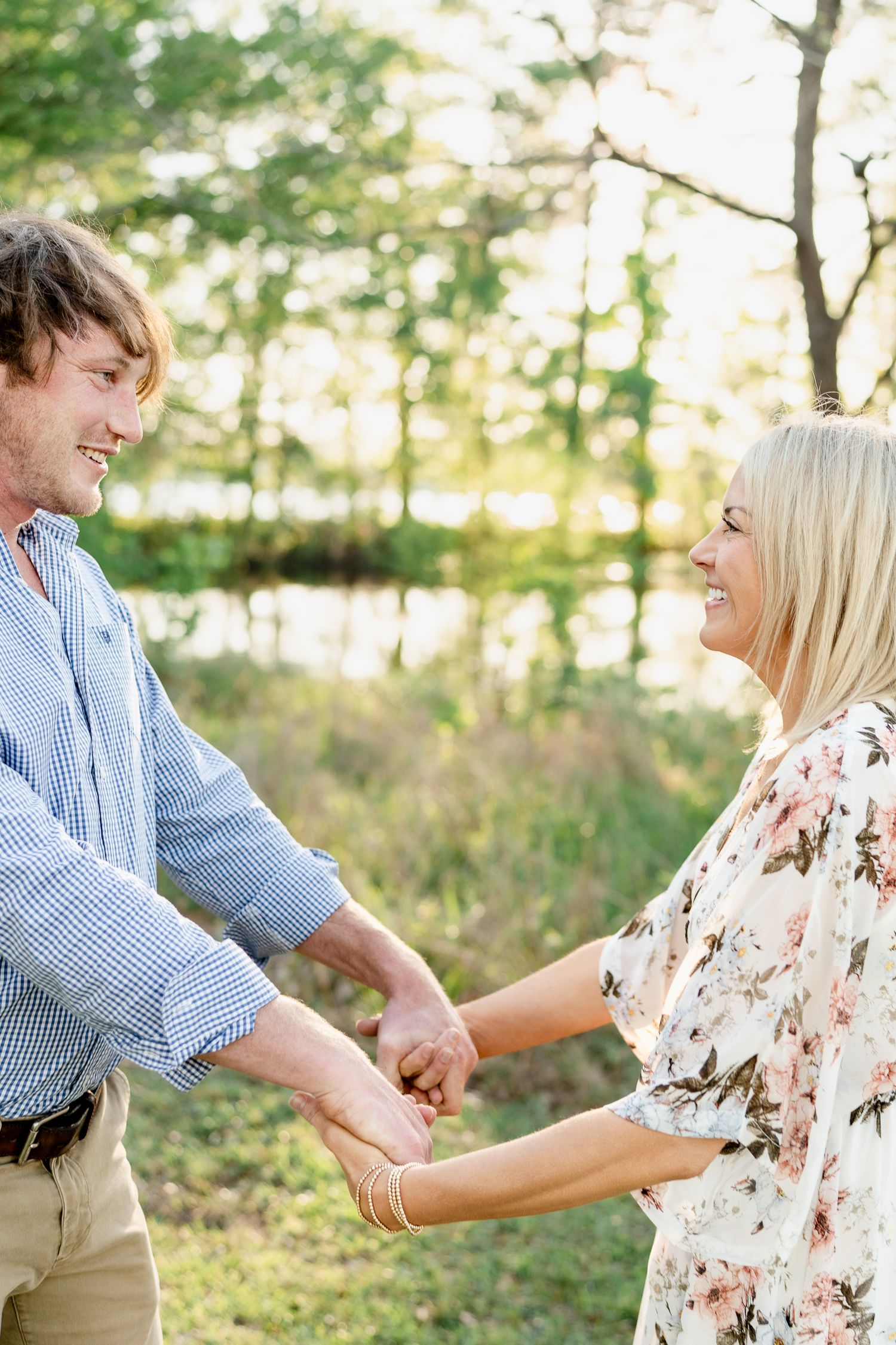 Joyful couple holding hands and laughing during outdoor engagement photoshoot.