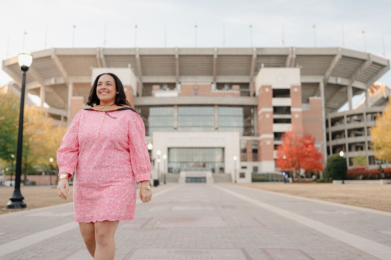 Person in pink ruffle dress walking through urban area with modern buildings in background.