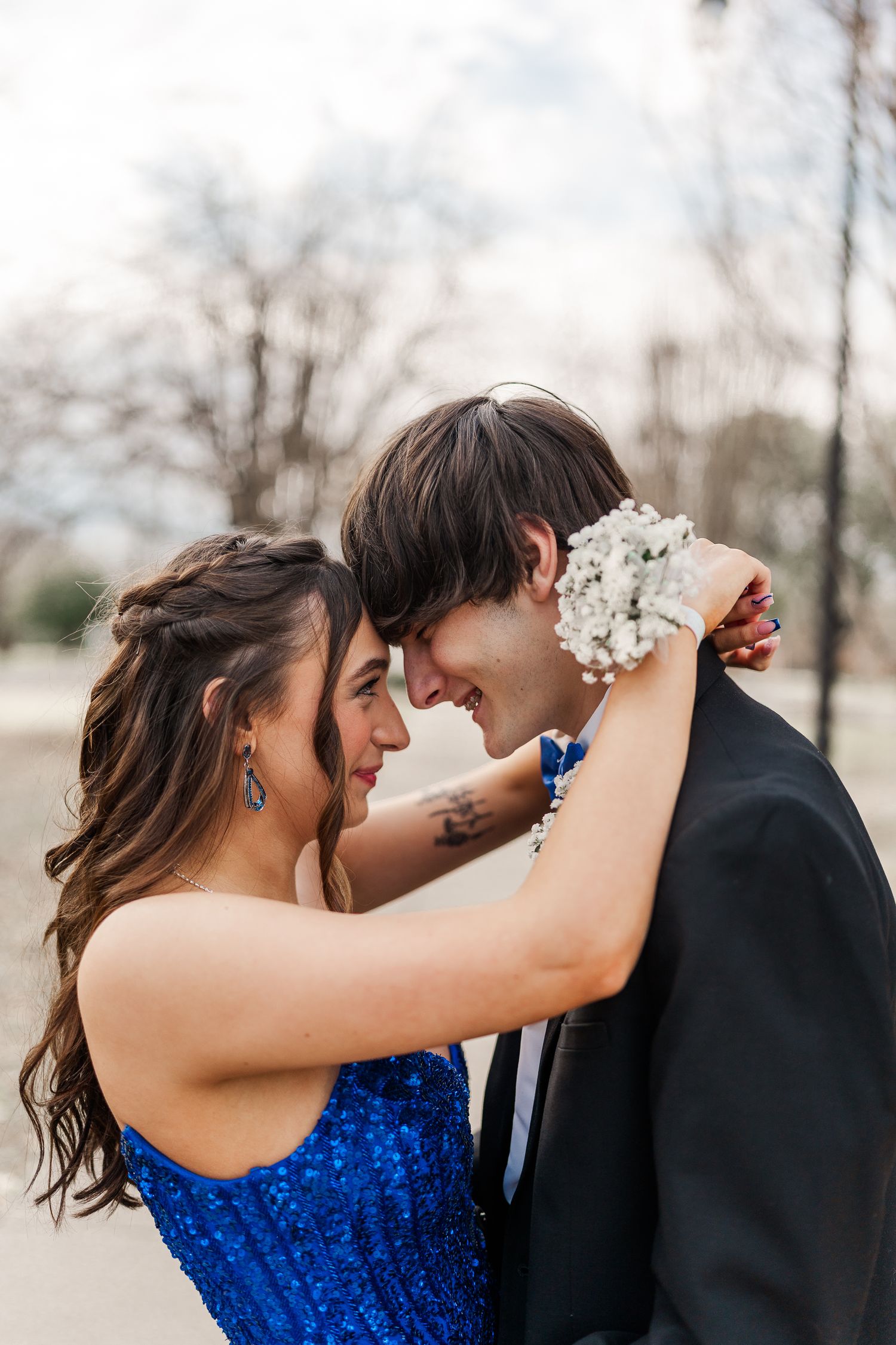 Couple shares romantic moment with white flowers during formal photo session outdoors.