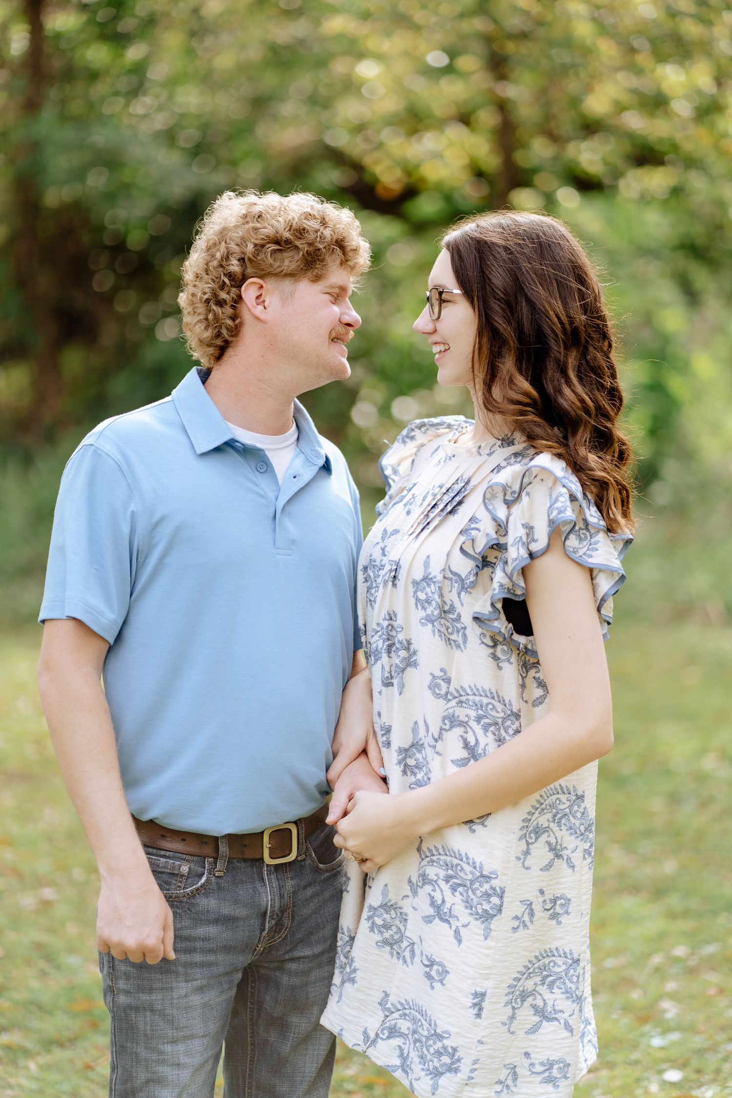 A couple poses and shares affectionate moments in a sunny outdoor garden setting.