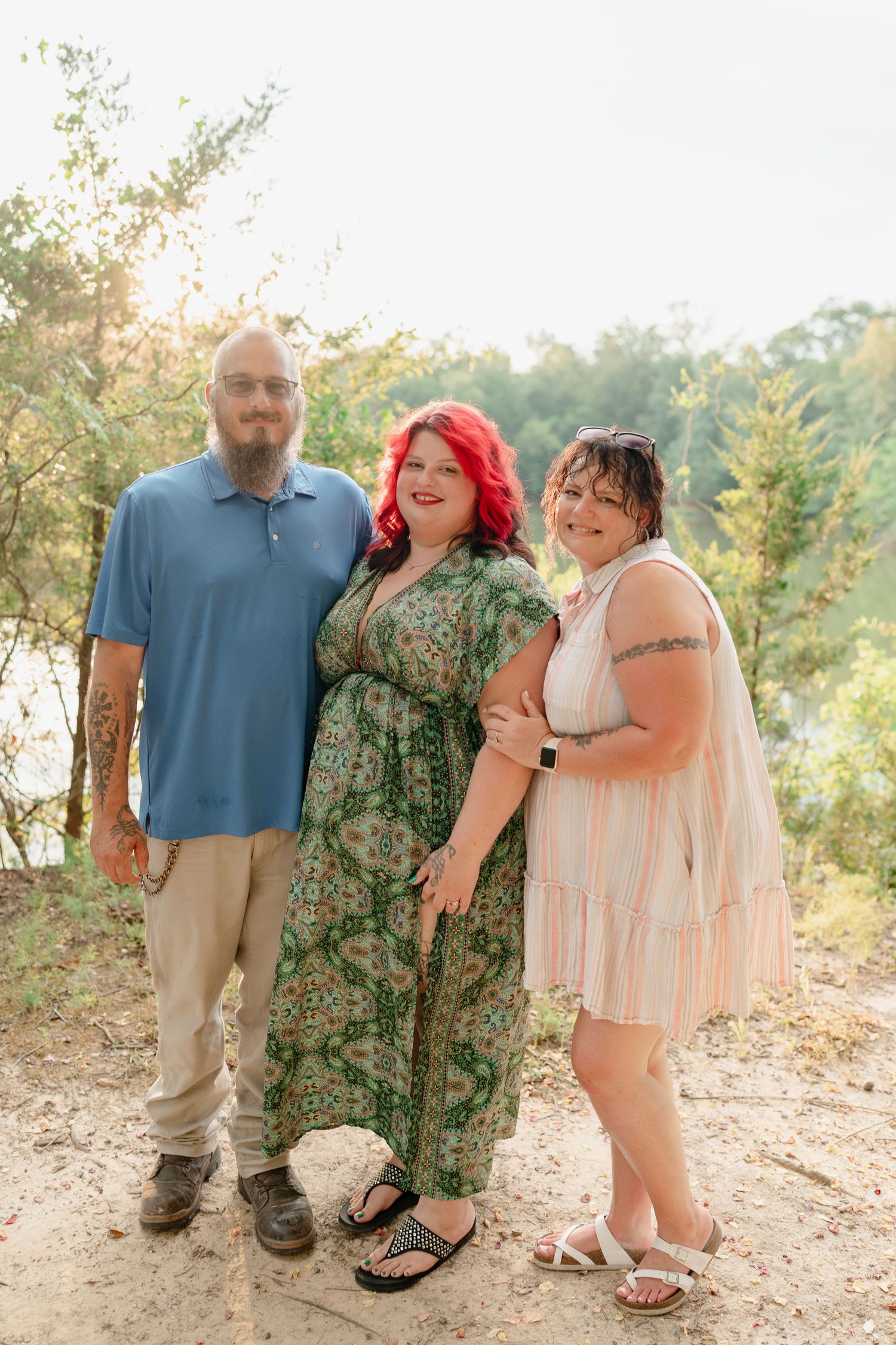 Group poses together for casual outdoor photos by a lake during golden hour.