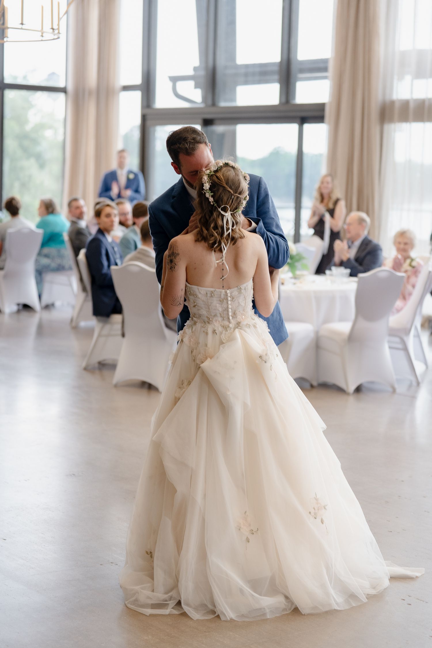 Elegant ballroom dance scene with flowing white gown and guests seated in background.