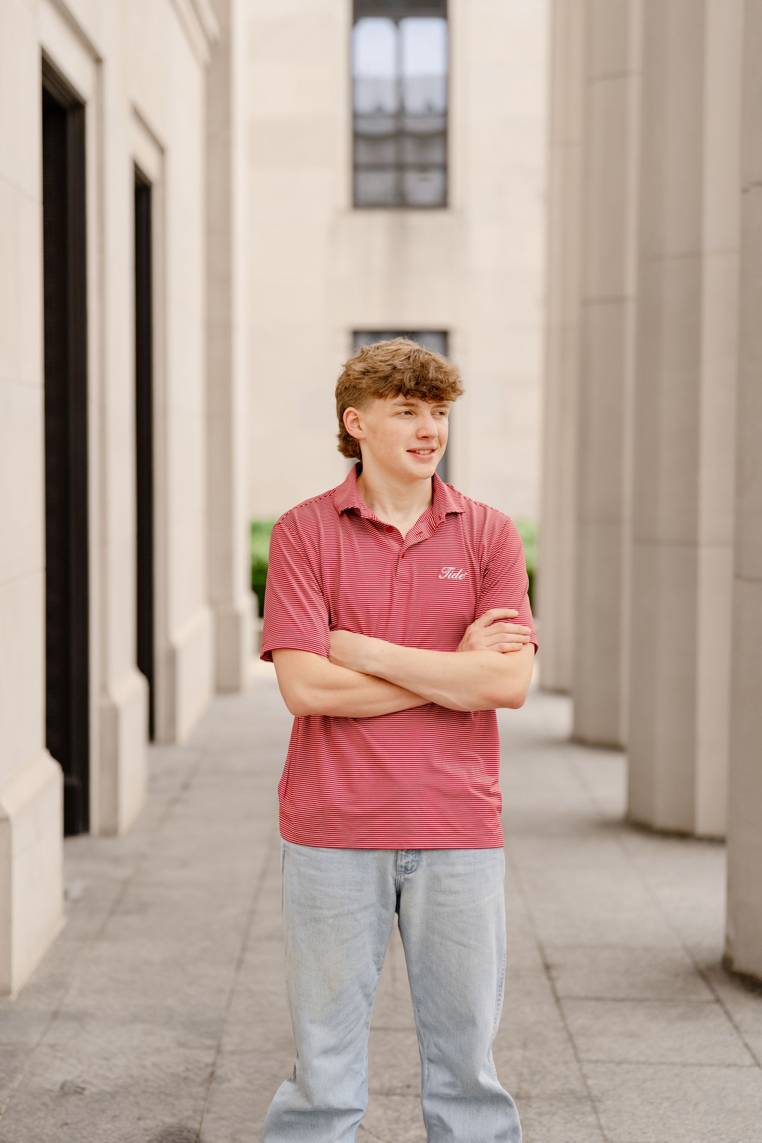 Portrait in striped pink polo between architectural columns and doorways.