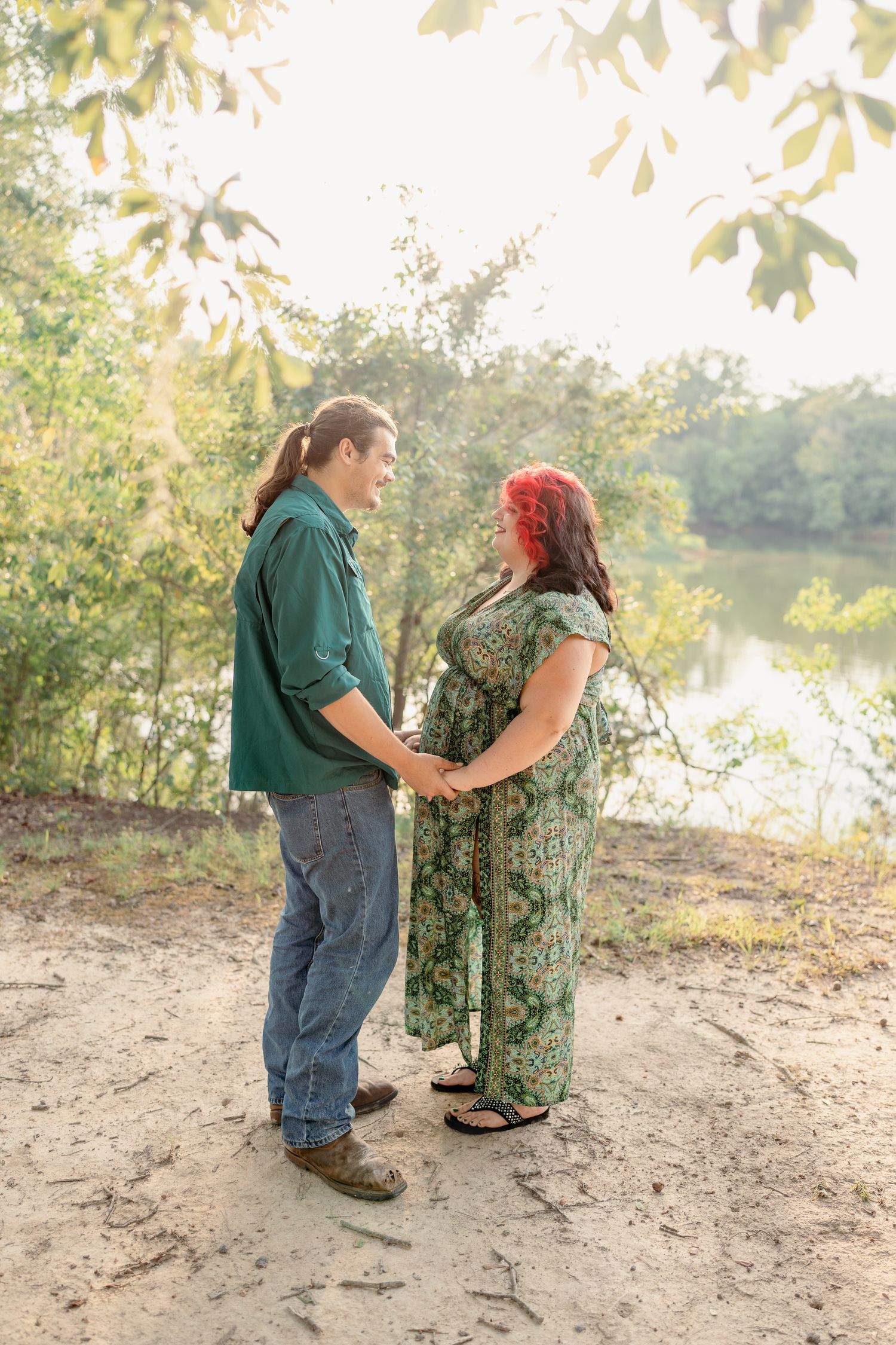 A couple shares a tender moment by a lake during a romantic outdoor photoshoot in autumn lighting.