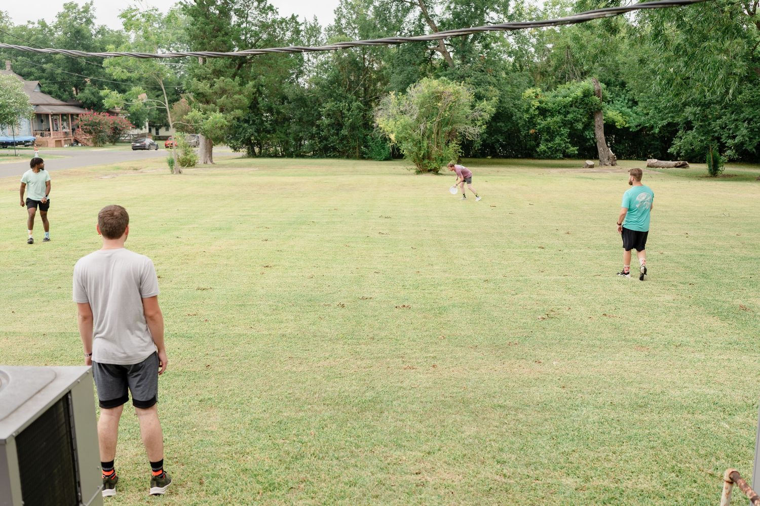 People playing ultimate frisbee on a grassy field during a sunny summer day.