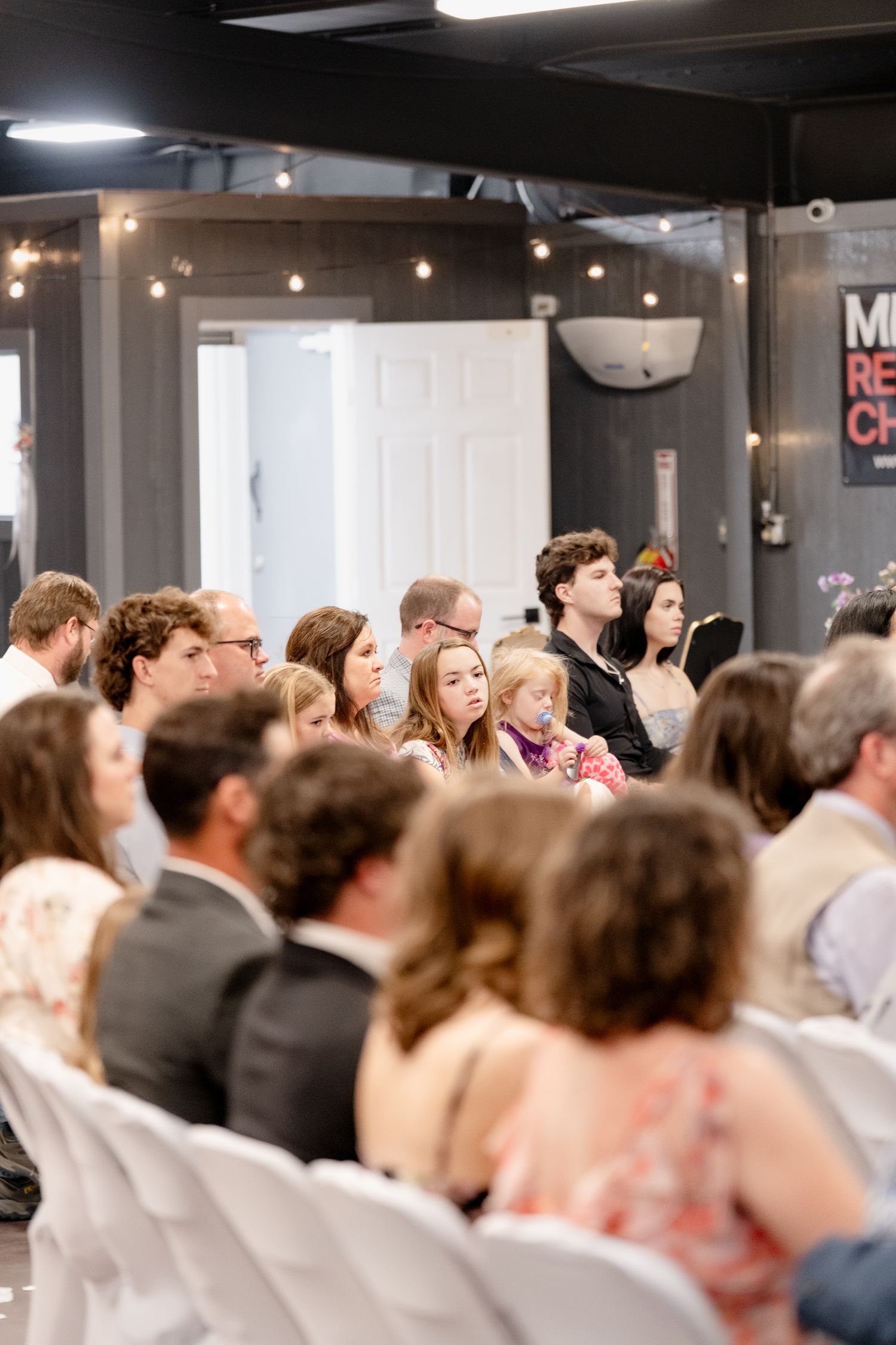A crowded indoor event venue with people seated in rows facing forward during a presentation or gathering.
