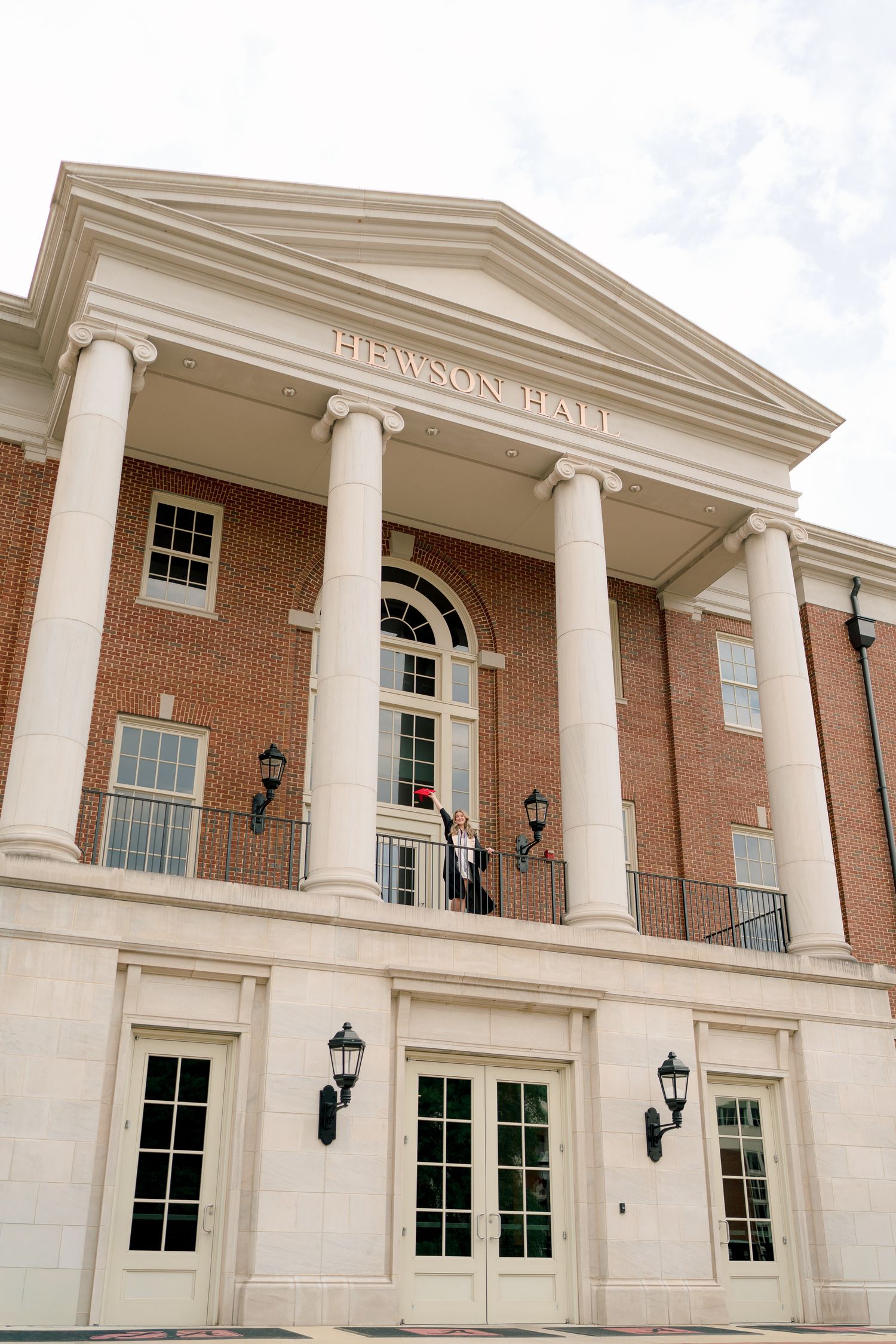 Elegant brick building with white columns and arched entrance features classical architectural details and ornate trim.