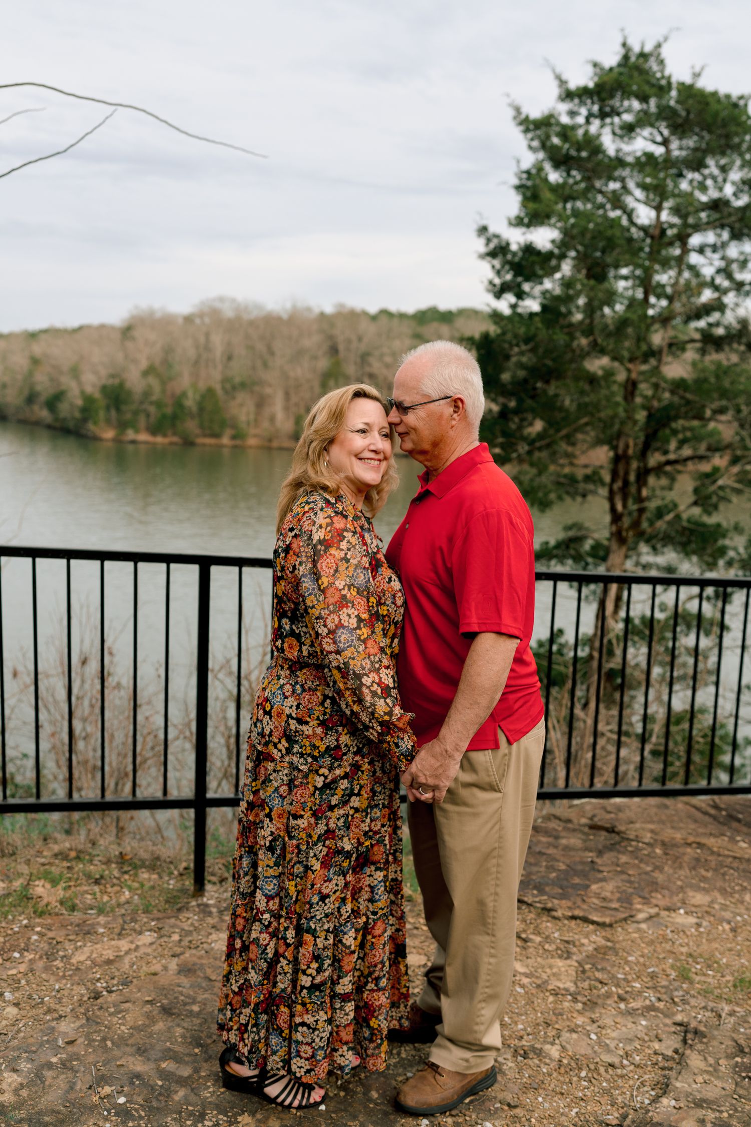 Loving mature couple holding hands and smiling at each other on a scenic lakeside overlook.