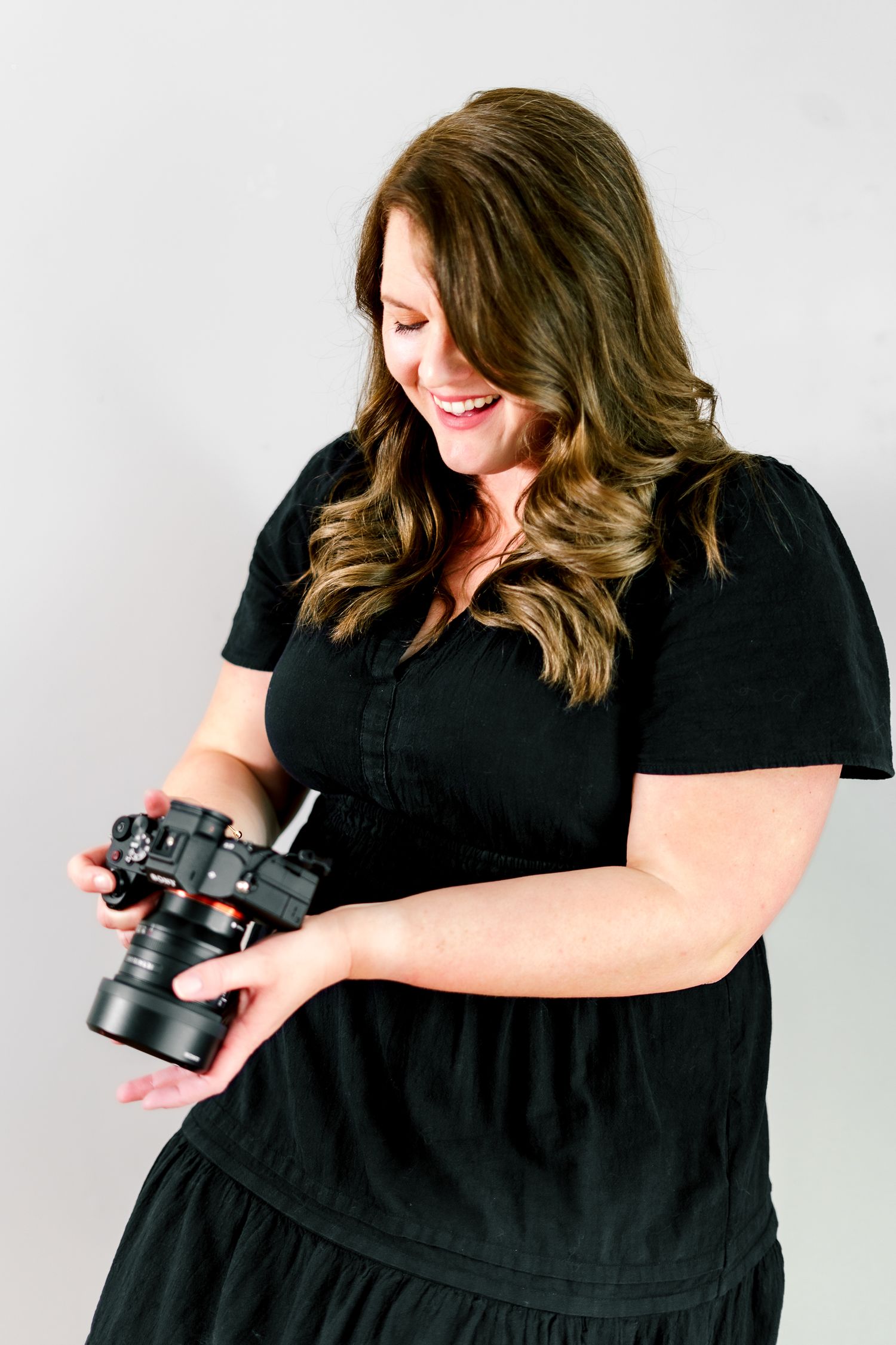 A person in black examines their camera while posing for lifestyle photos.
