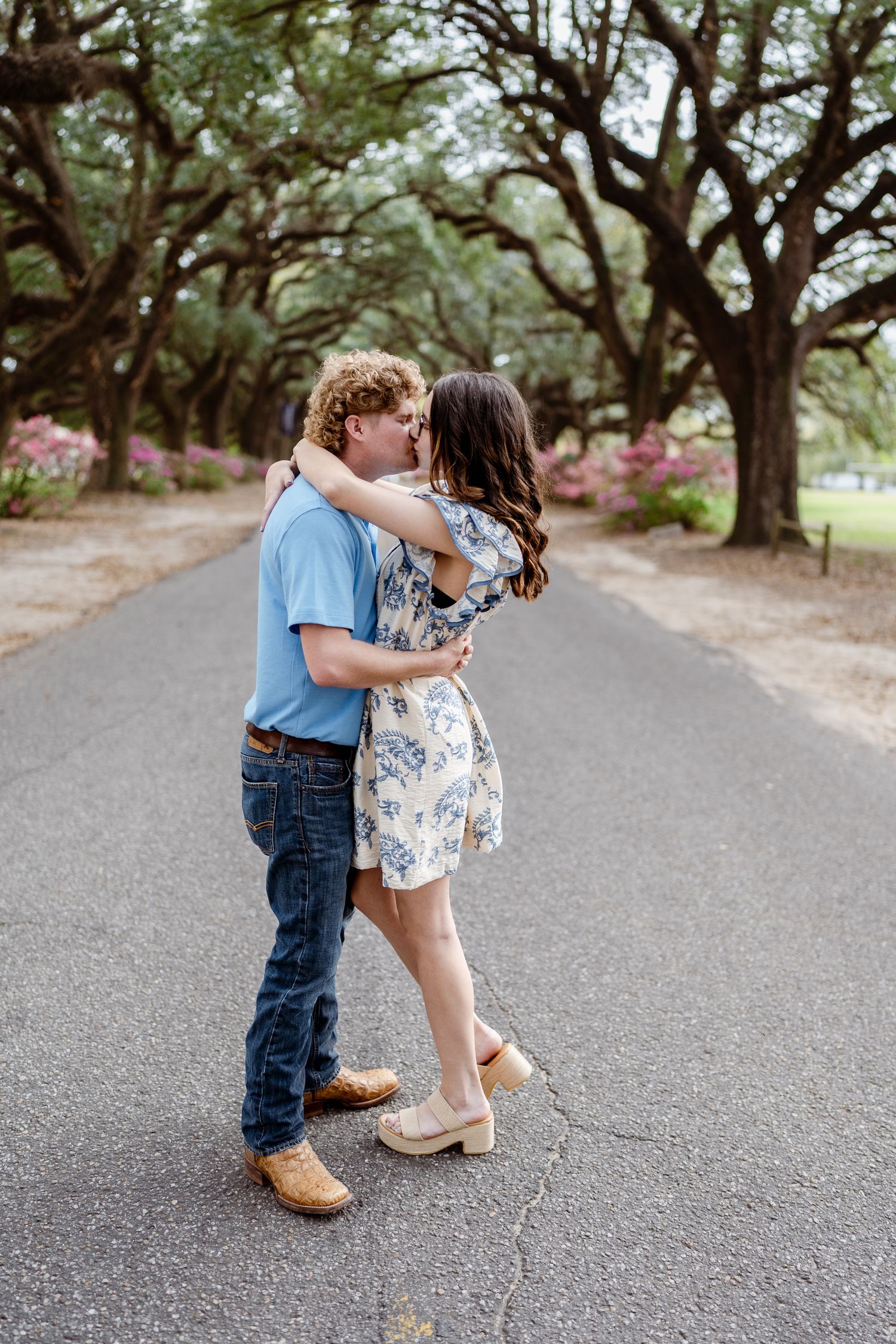 Romantic couple dance and embrace on path beneath blooming trees.