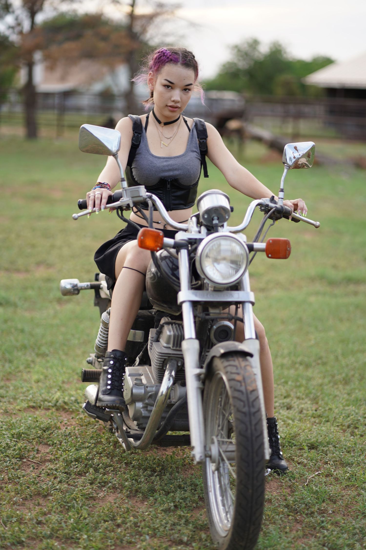 A motorcycle enthusiast poses on a vintage-style bike in casual athletic wear.
