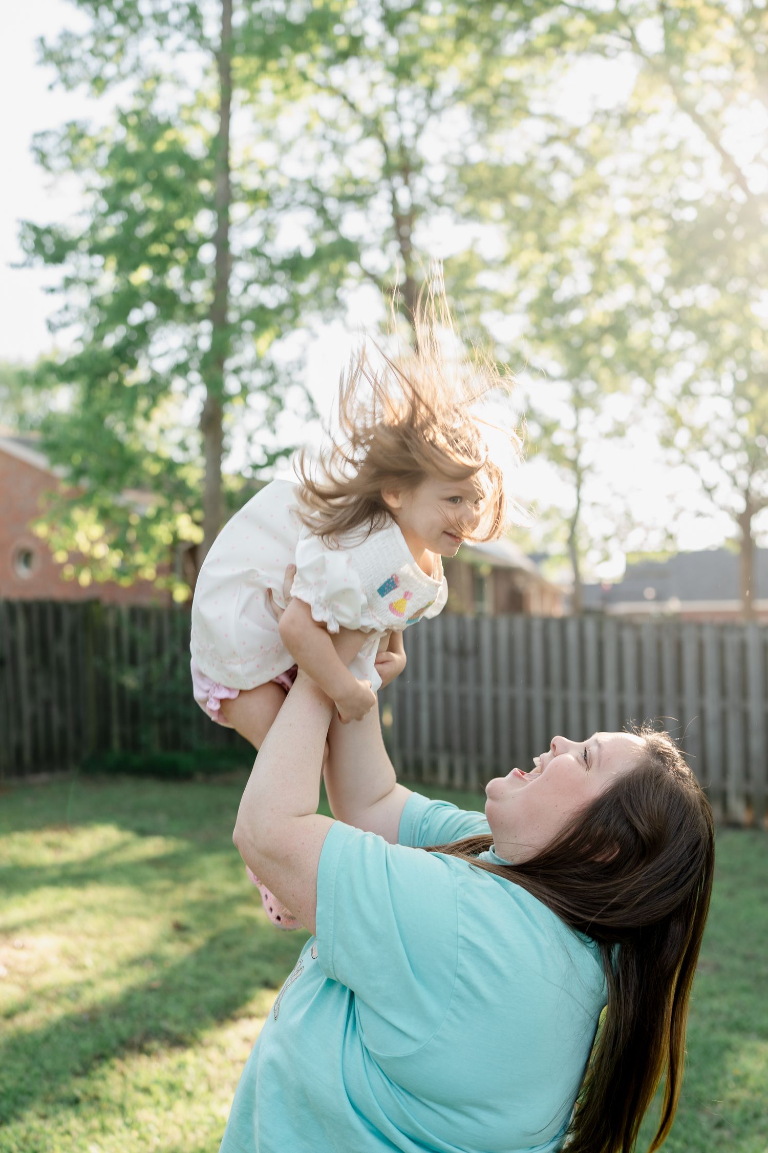 Playful moment between parent and child against sunny backyard setting.