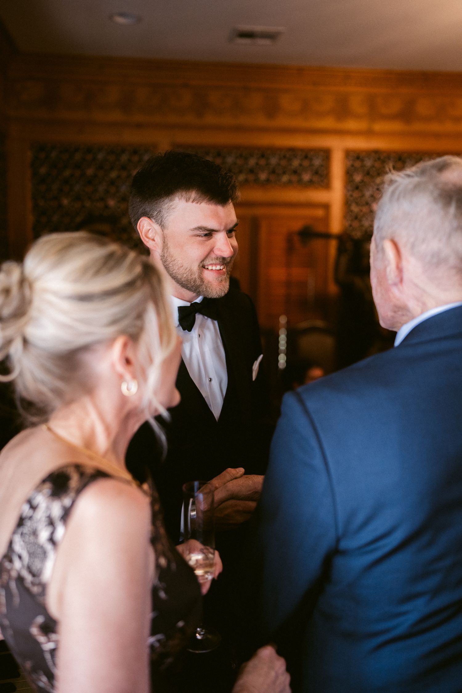 Wedding guests engaged in lively conversation at an elegant indoor reception.