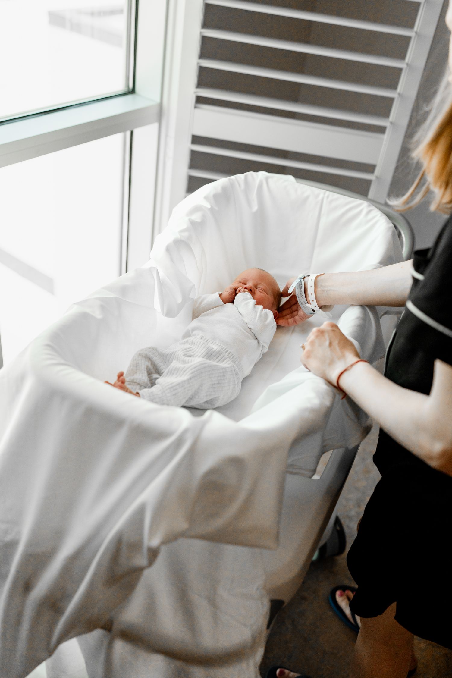 Newborn baby wearing white clothing lying on soft white bedding in sequential photos.