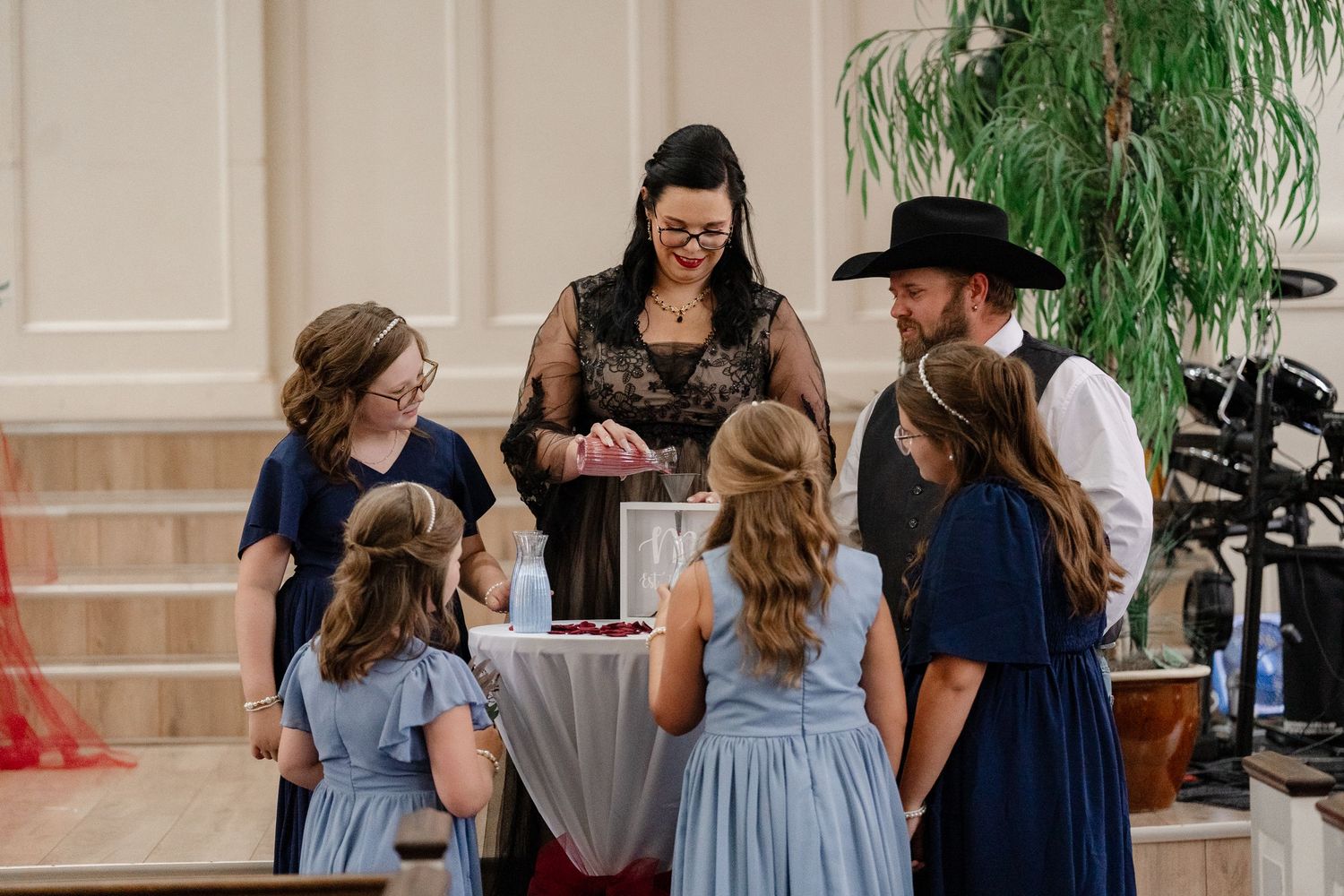 Wedding party poses in coordinated navy and gray outfits inside an elegant venue.