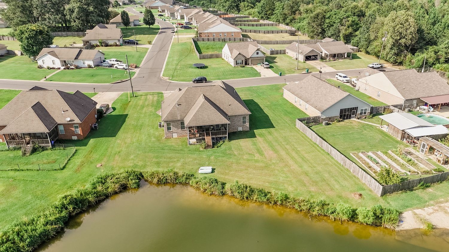 Aerial panoramic view of suburban residential neighborhood with green lawns and trees surrounding single-story homes.
