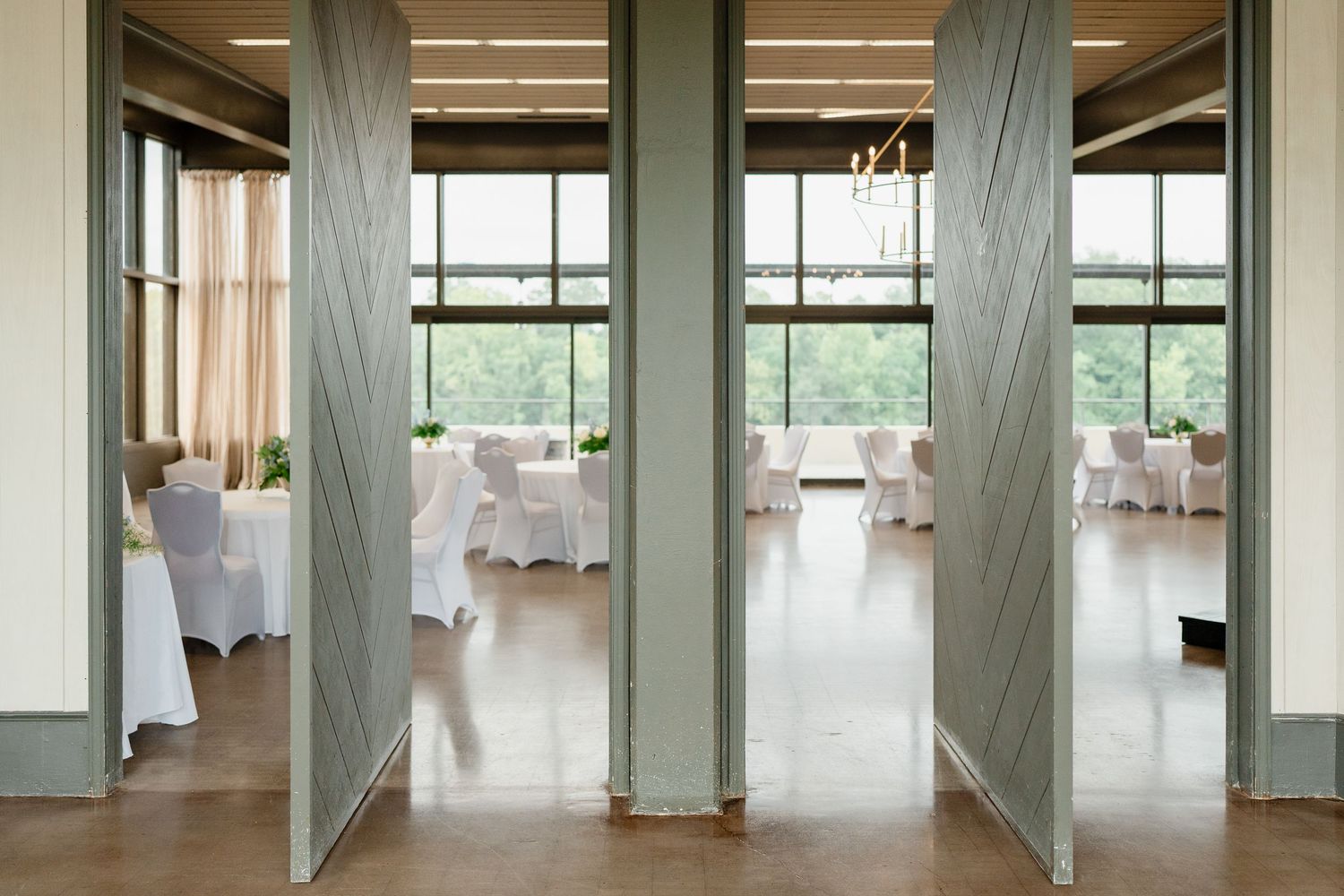 A modern minimalist event space with white columns and large windows offering natural light and an open floor plan.